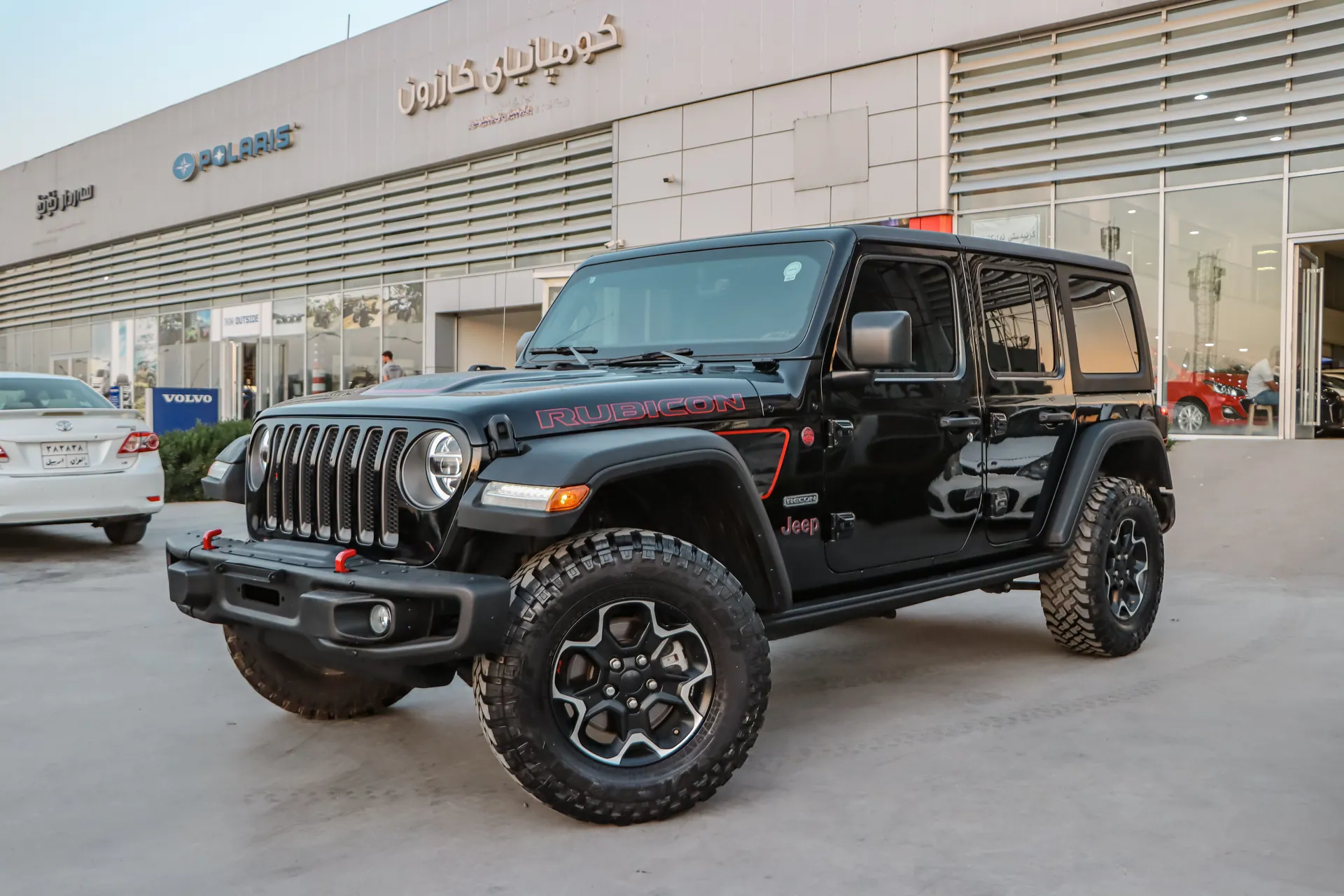 Black Jeep Wrangler Rubicon parked at a dealership showcasing its rugged design and glossy finish.