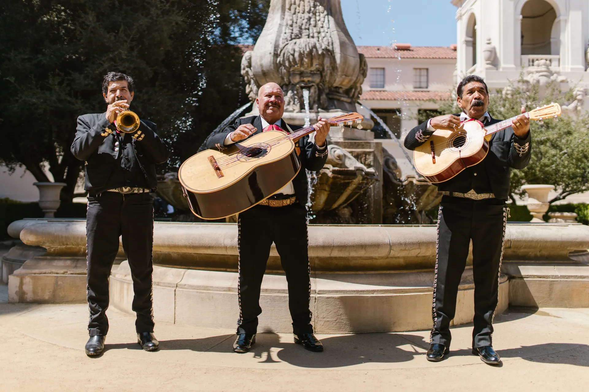 Traditional mariachi band playing music outdoors near a grand fountain, showcasing cultural heritage.