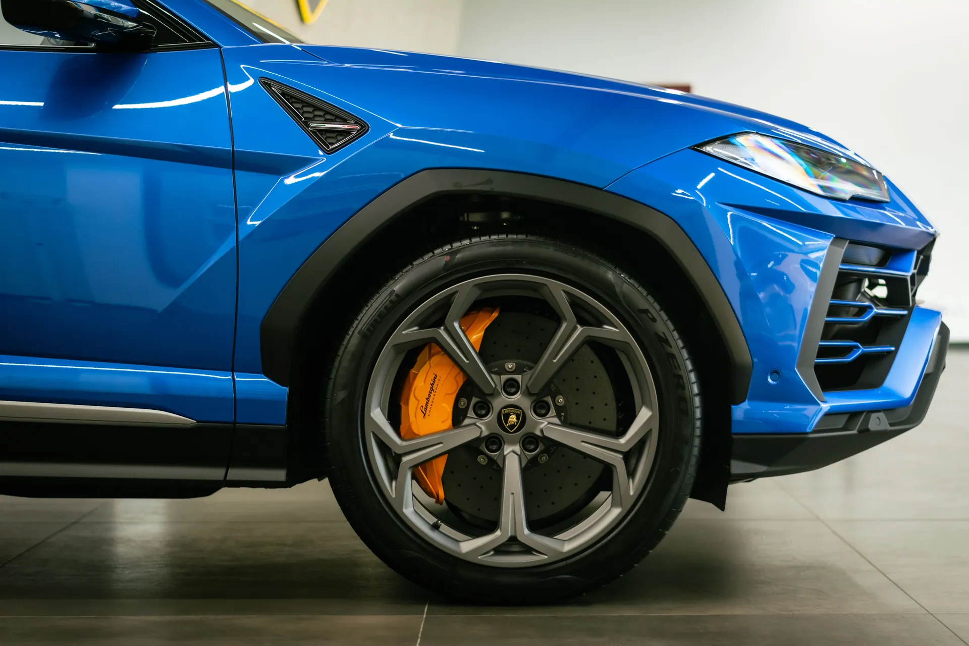 Detailed close-up of a blue Lamborghini sports car showcasing the wheel and design.