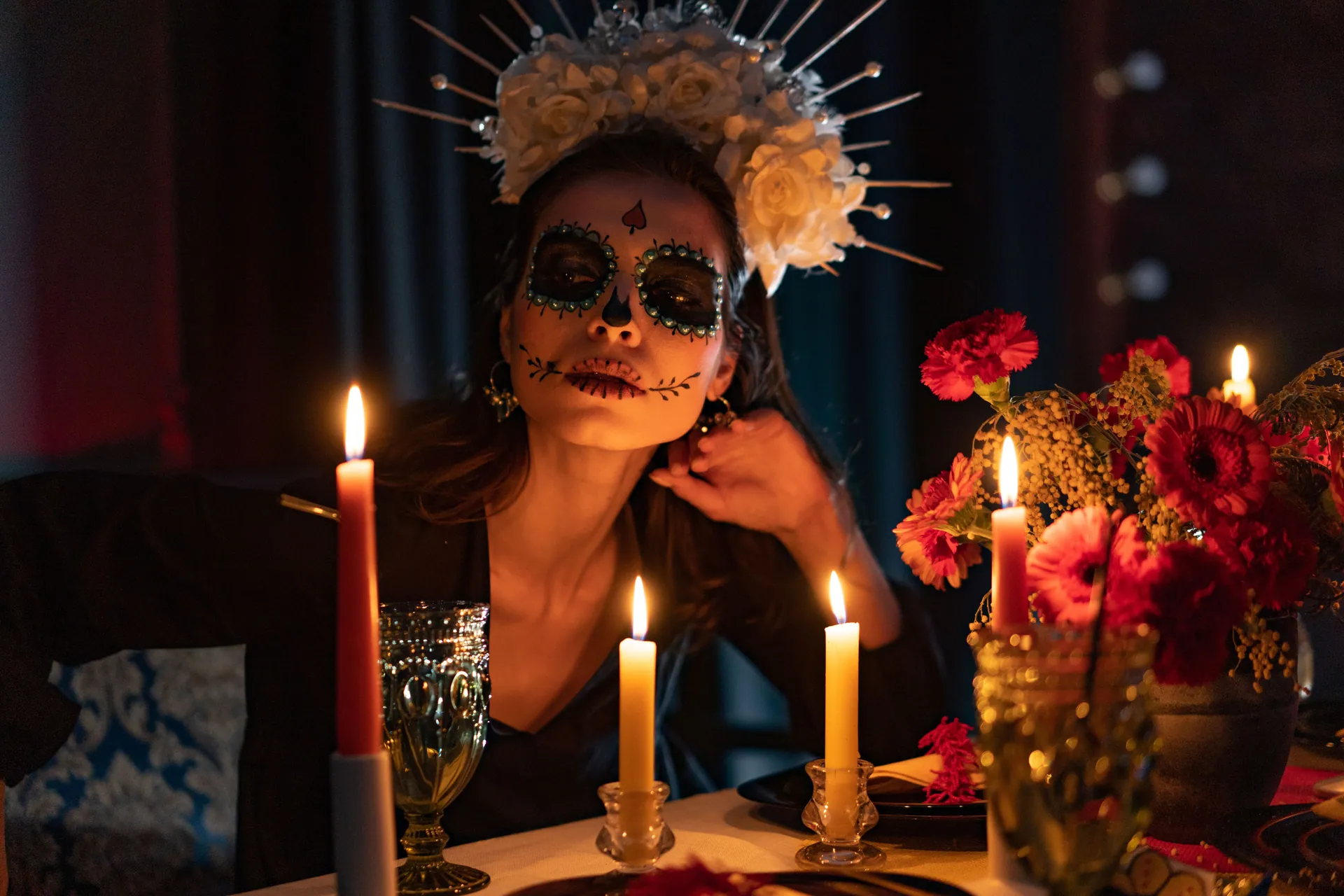 A beautifully decorated woman celebrating Día de los Muertos with candles and flowers.