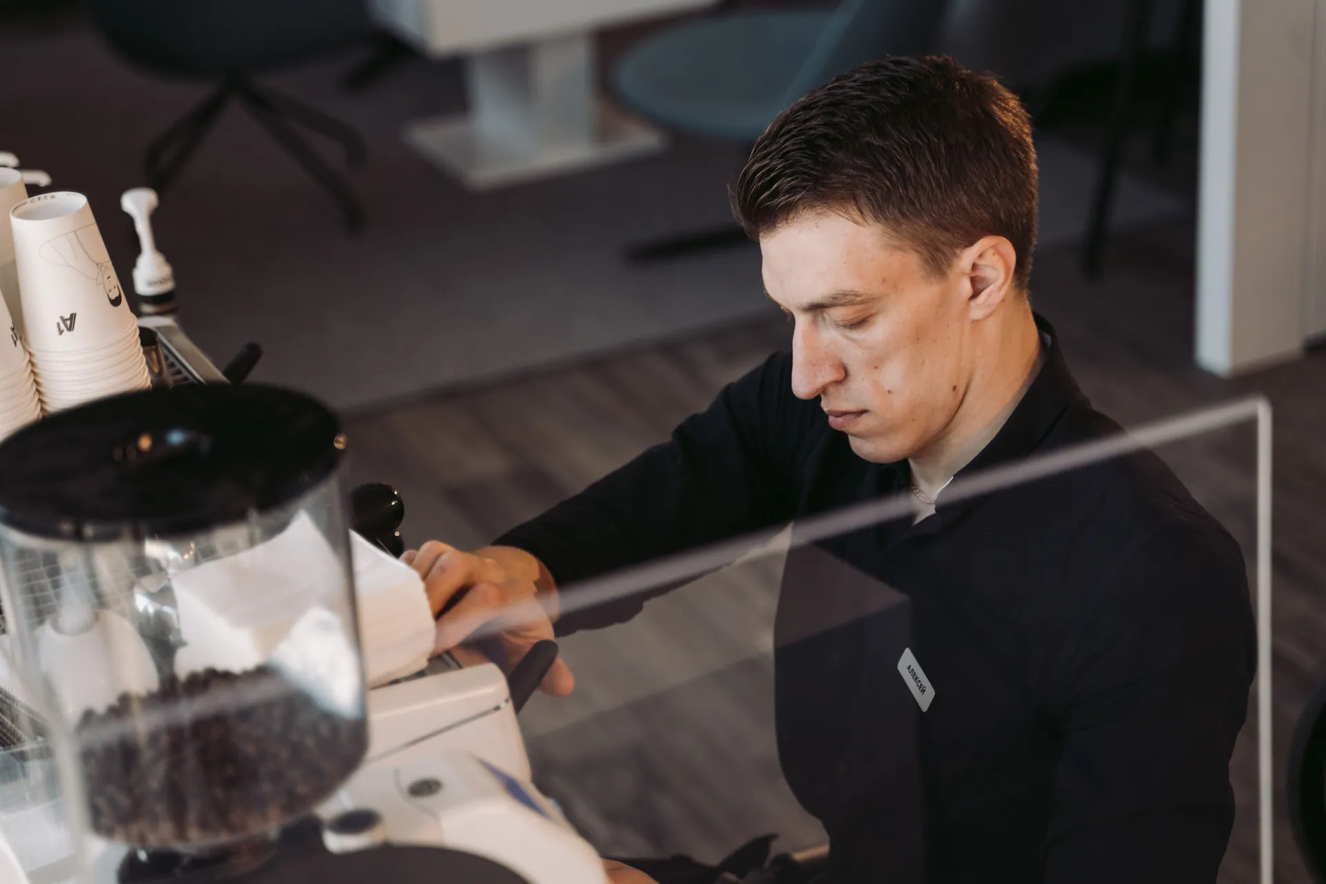 Barista focused on brewing coffee in a modern cafe setting.