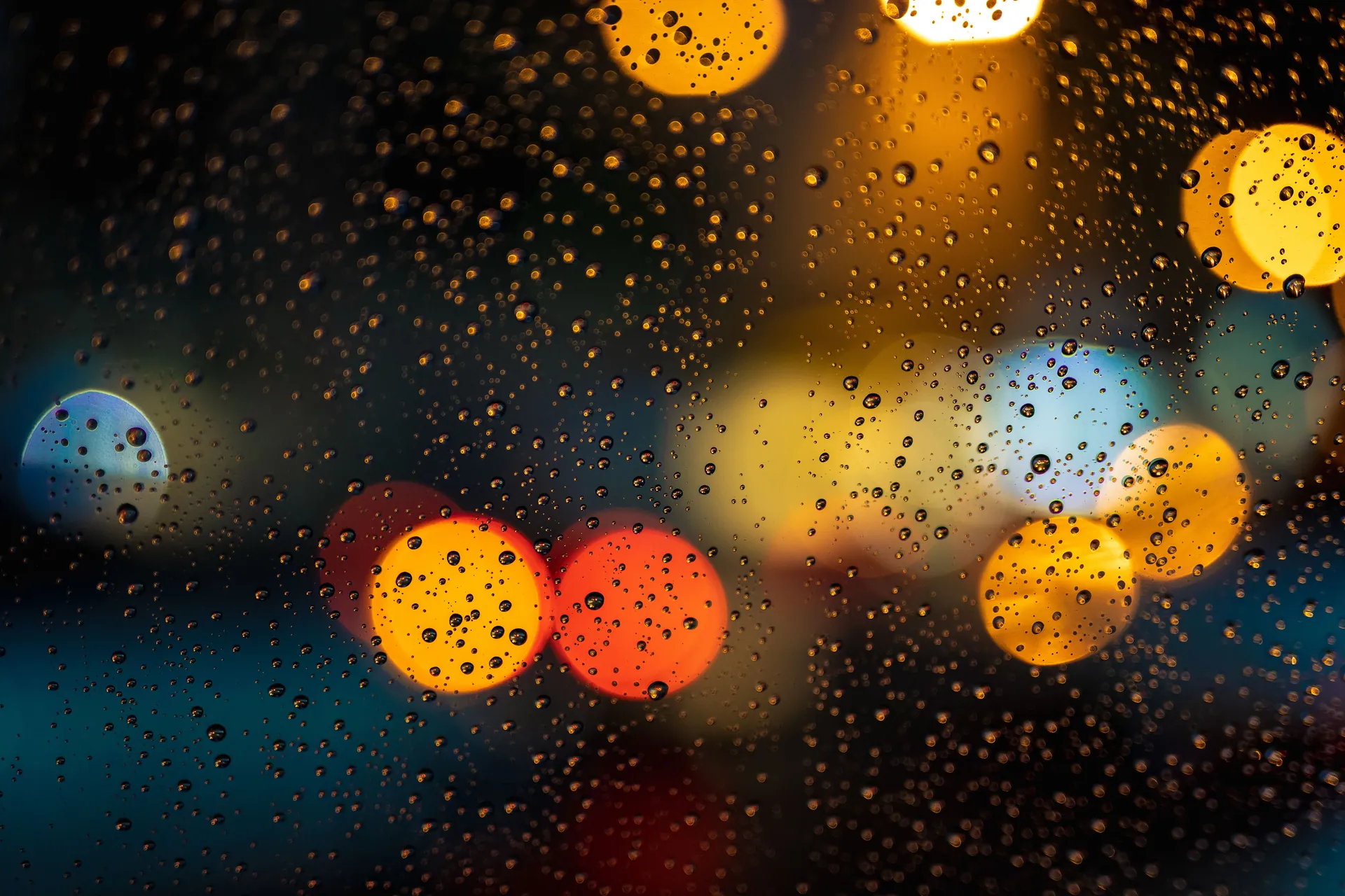 Raindrops on window with vibrant bokeh lights creating an abstract nighttime view.