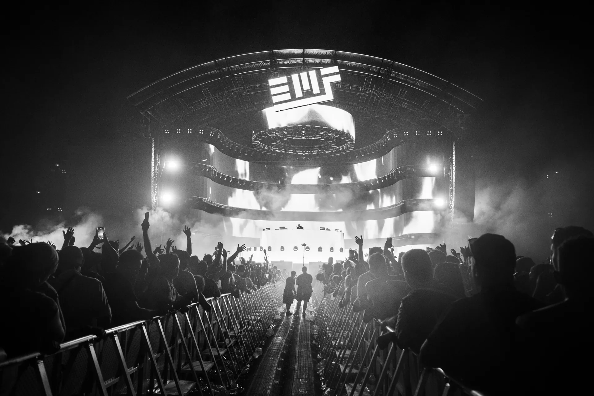 Black and white photo capturing a live concert with an energetic audience and dynamic stage lighting.