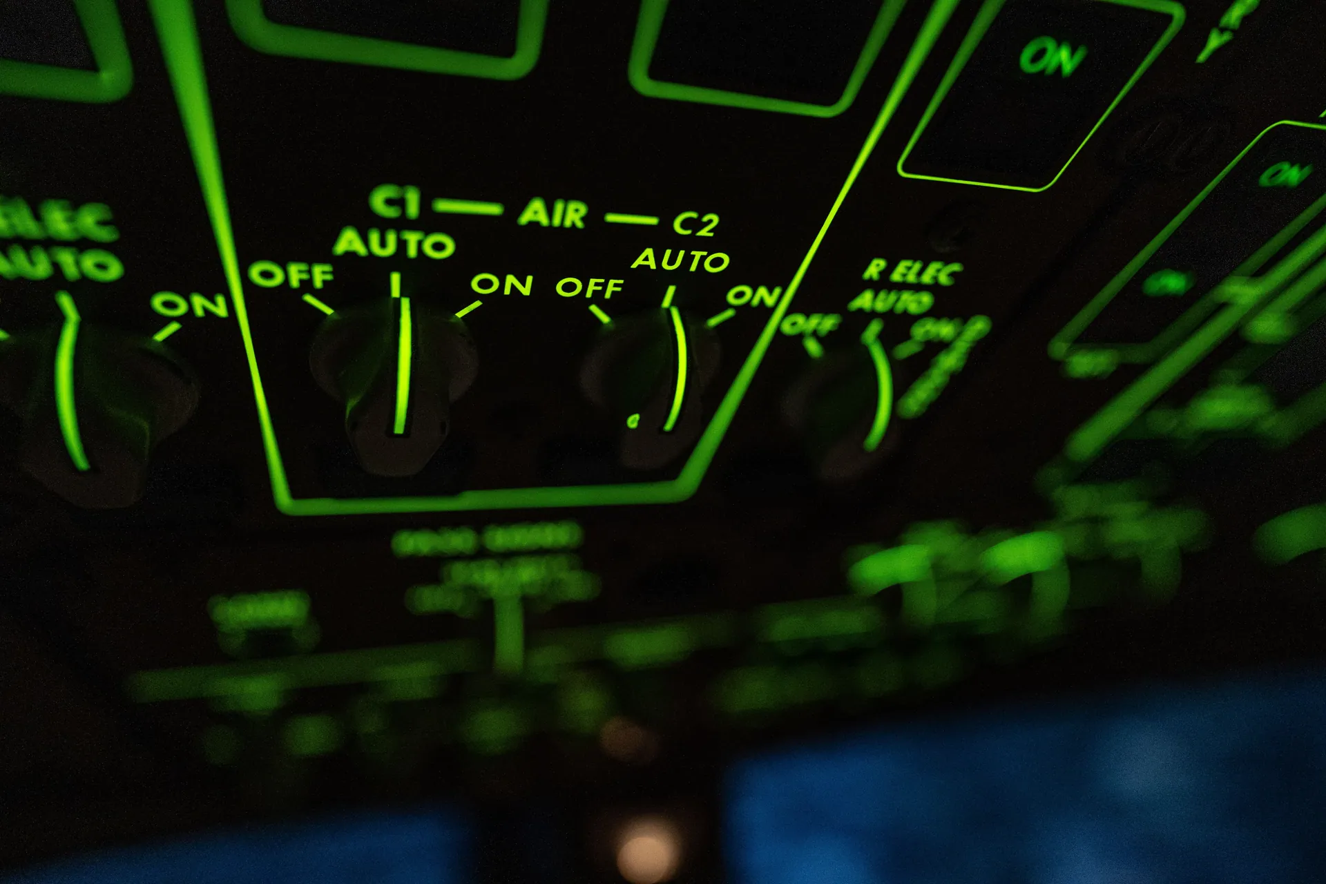 Close-up shot of illuminated aircraft cockpit controls with green lighting.