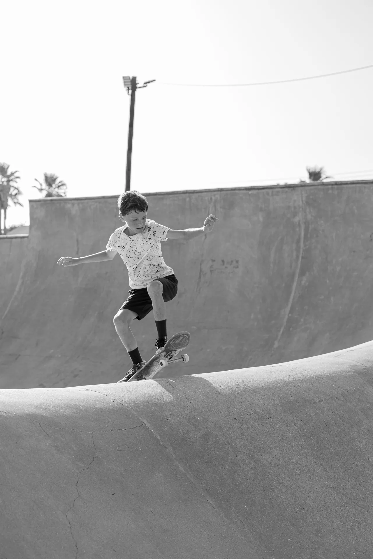 Young boy performing a skateboard trick at Galveston skatepark in black and white.