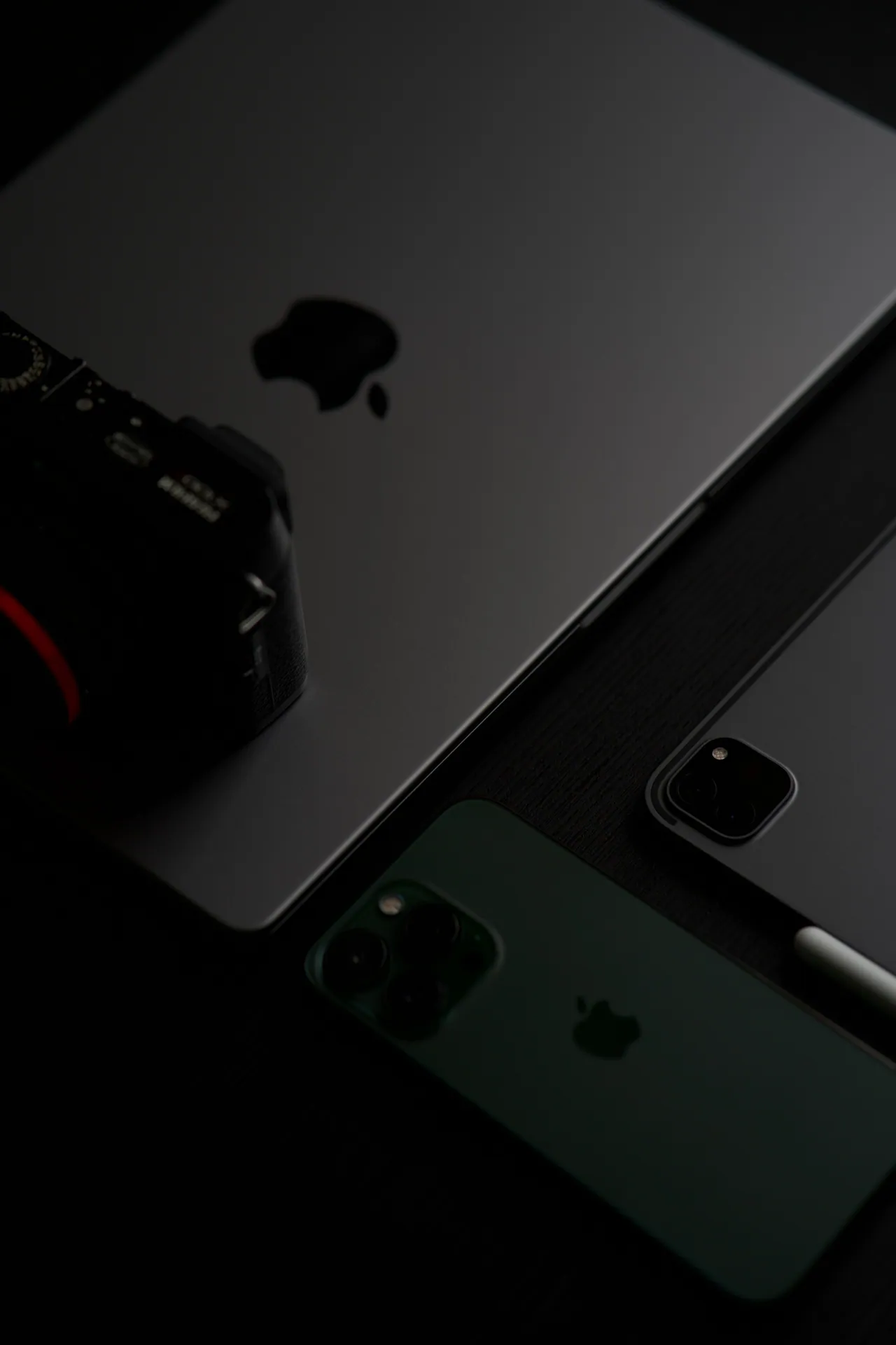 Close-up of electronic devices including a laptop, smartphone, and camera.
