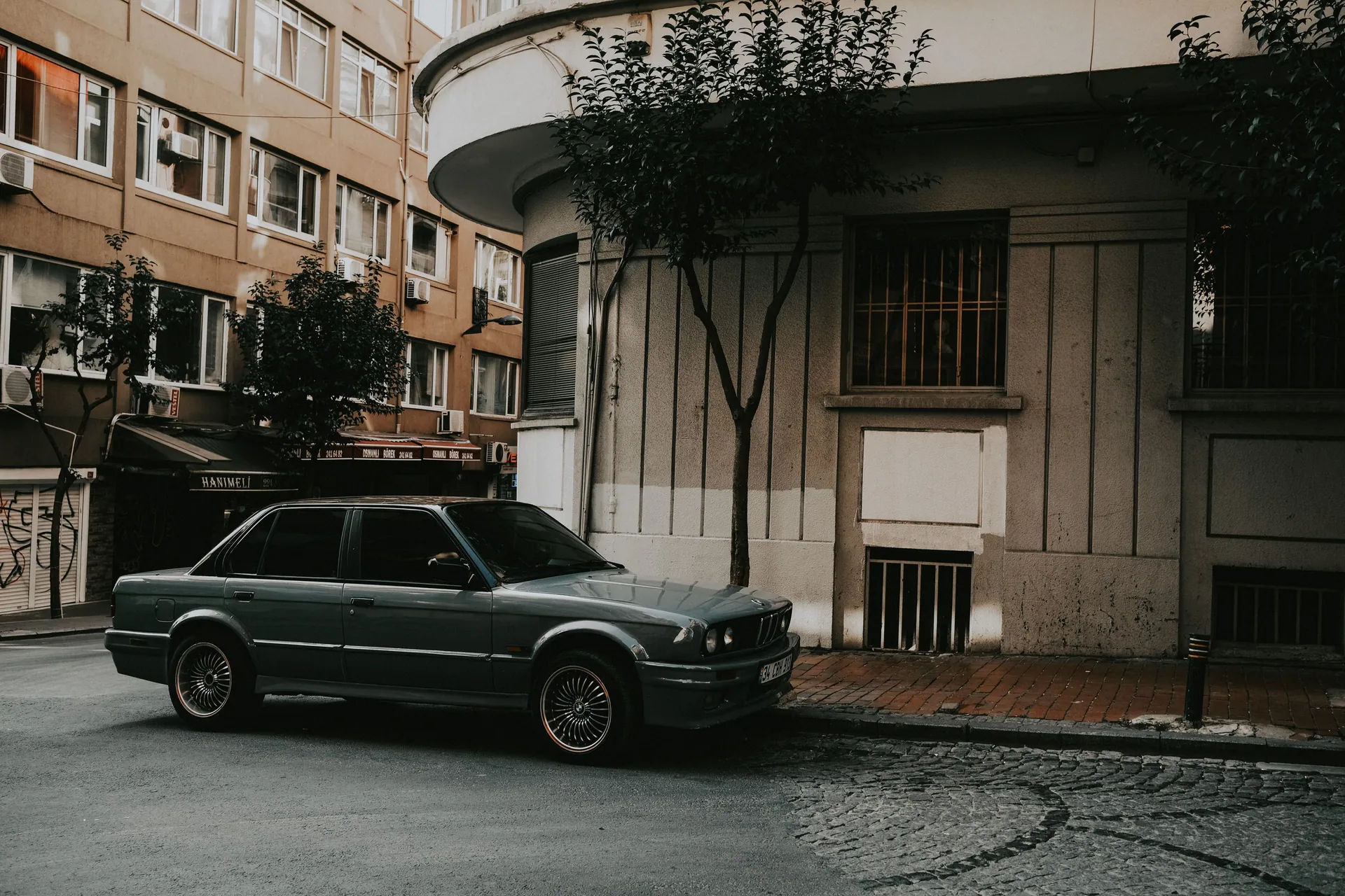 Classic vintage car parked by a building on a city street, emphasizing urban architecture.