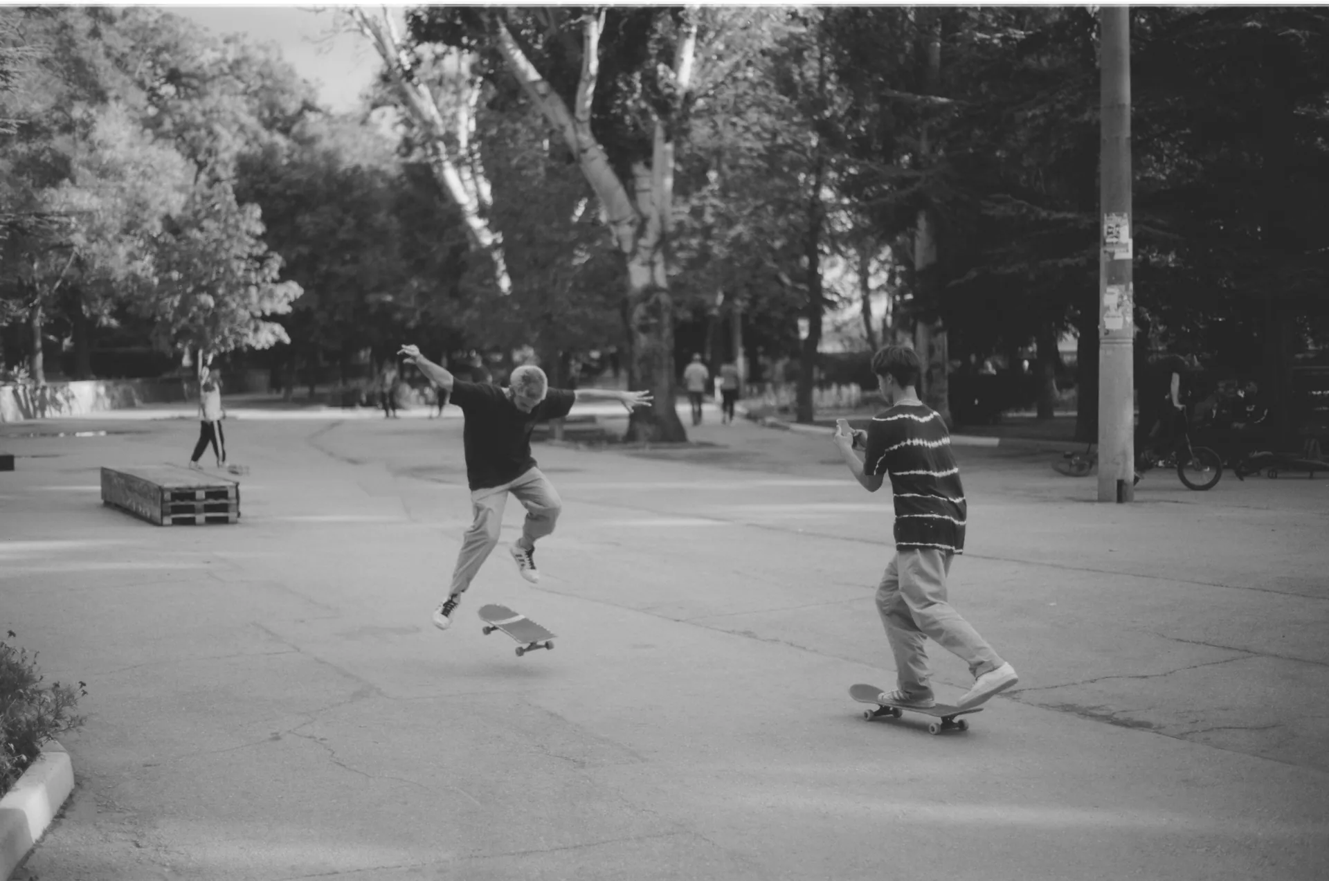Two skateboarders performing tricks in a park, captured in black and white, showcasing dynamic motion and urban lifestyle.