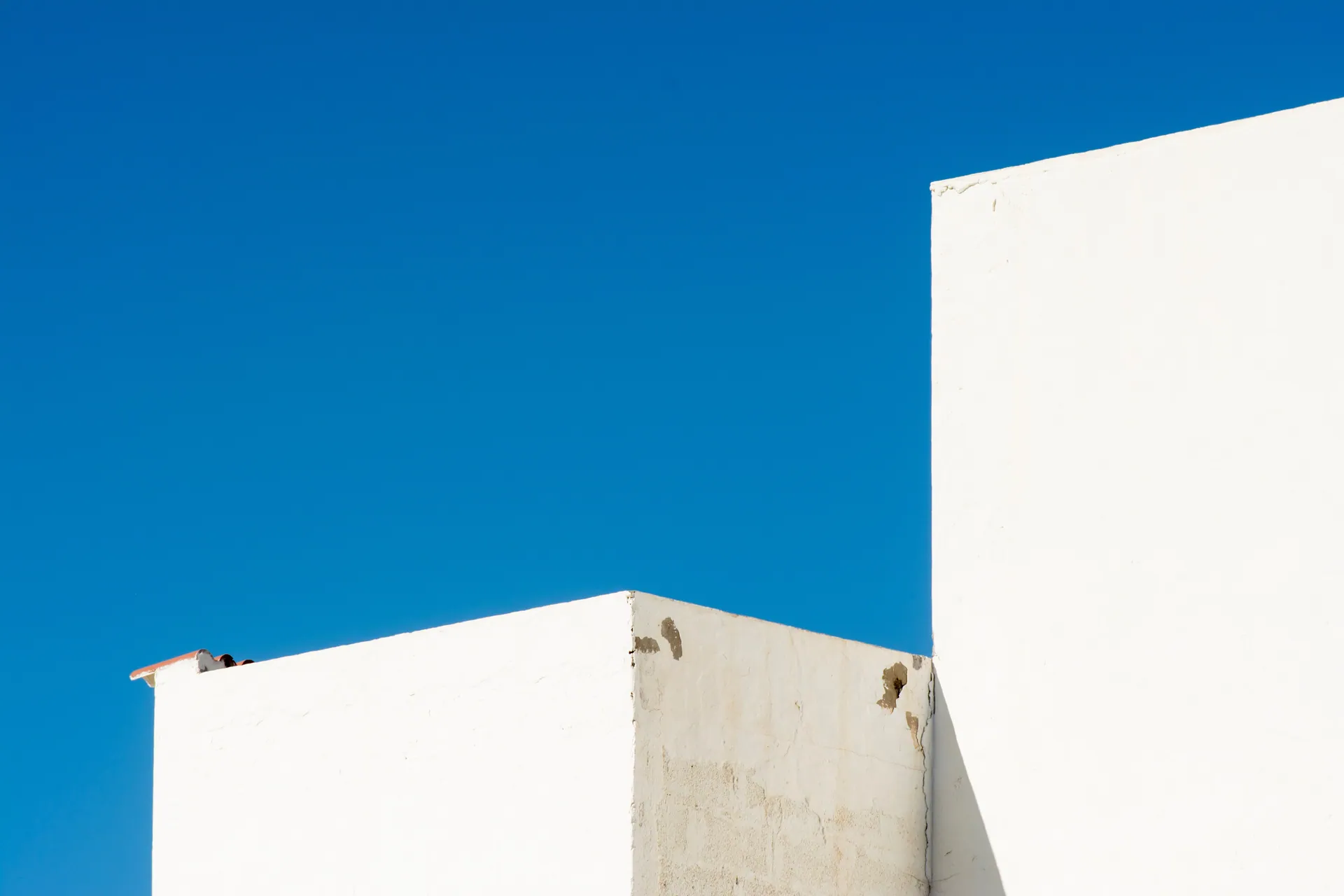 A minimalist composition of white buildings set against a vibrant blue sky, highlighting urban architecture.