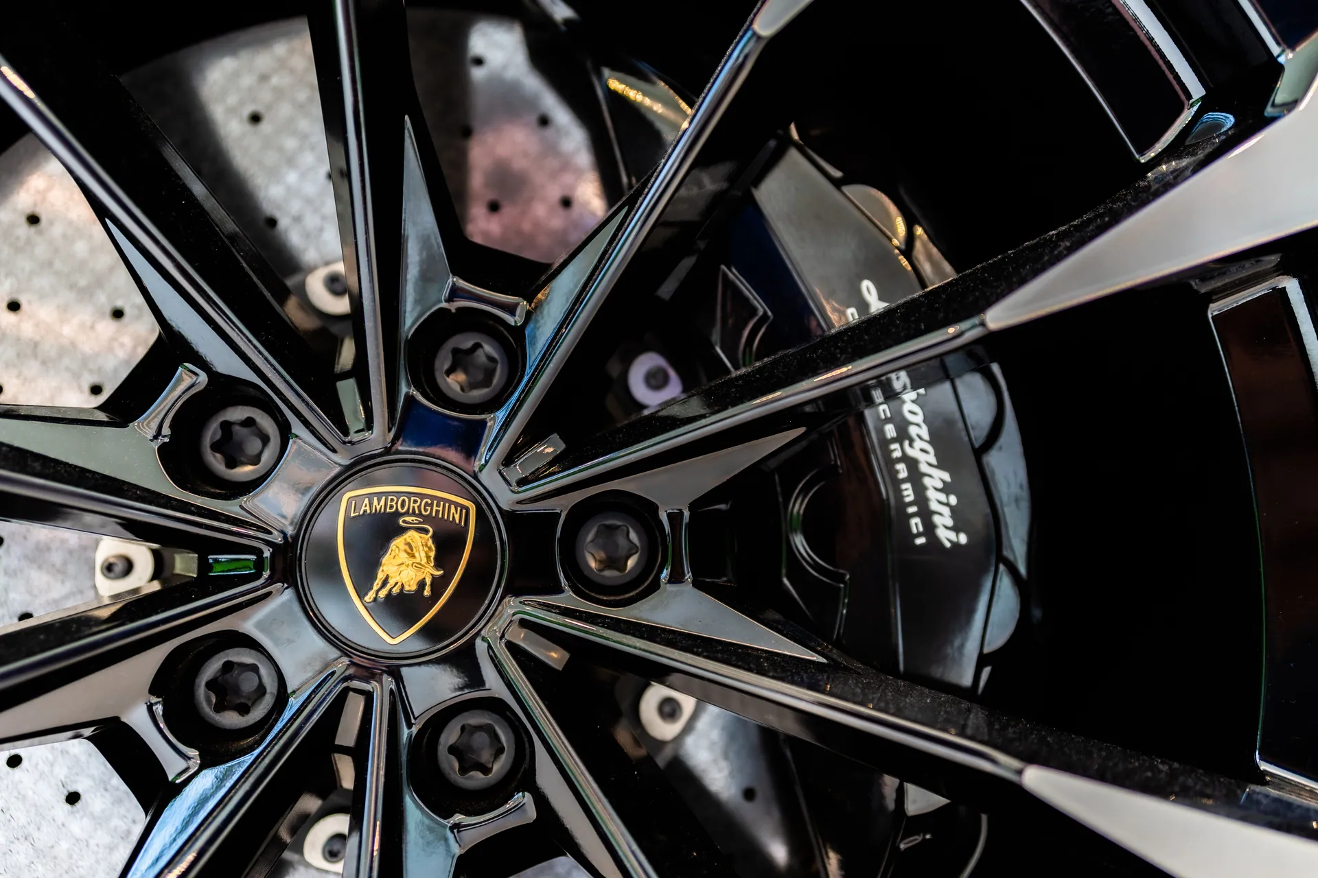 Detailed close-up of a Lamborghini wheel rim showcasing the iconic logo and brake caliper.