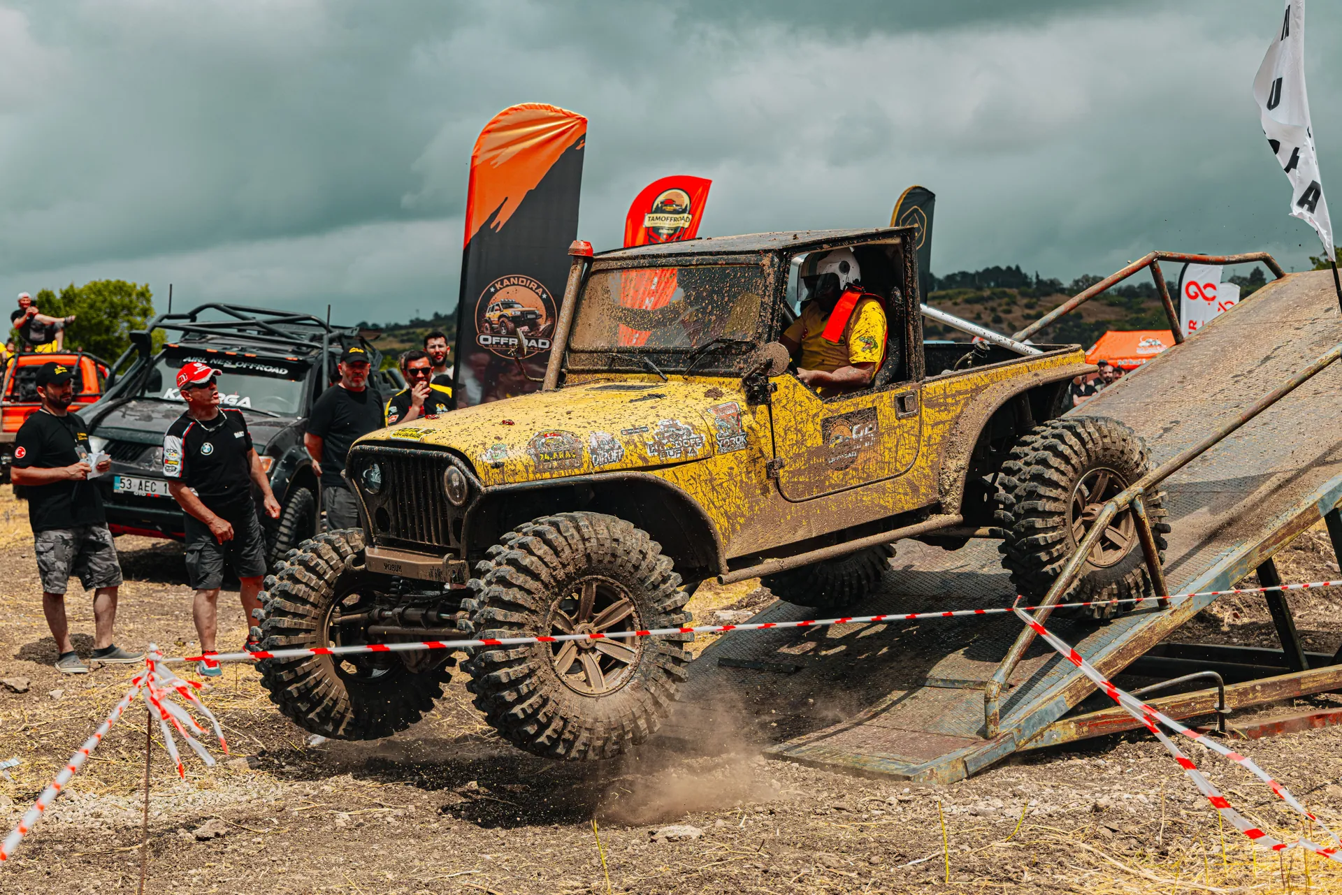 Dynamic off-road jeep race with muddy terrain and spectators observing the competition.