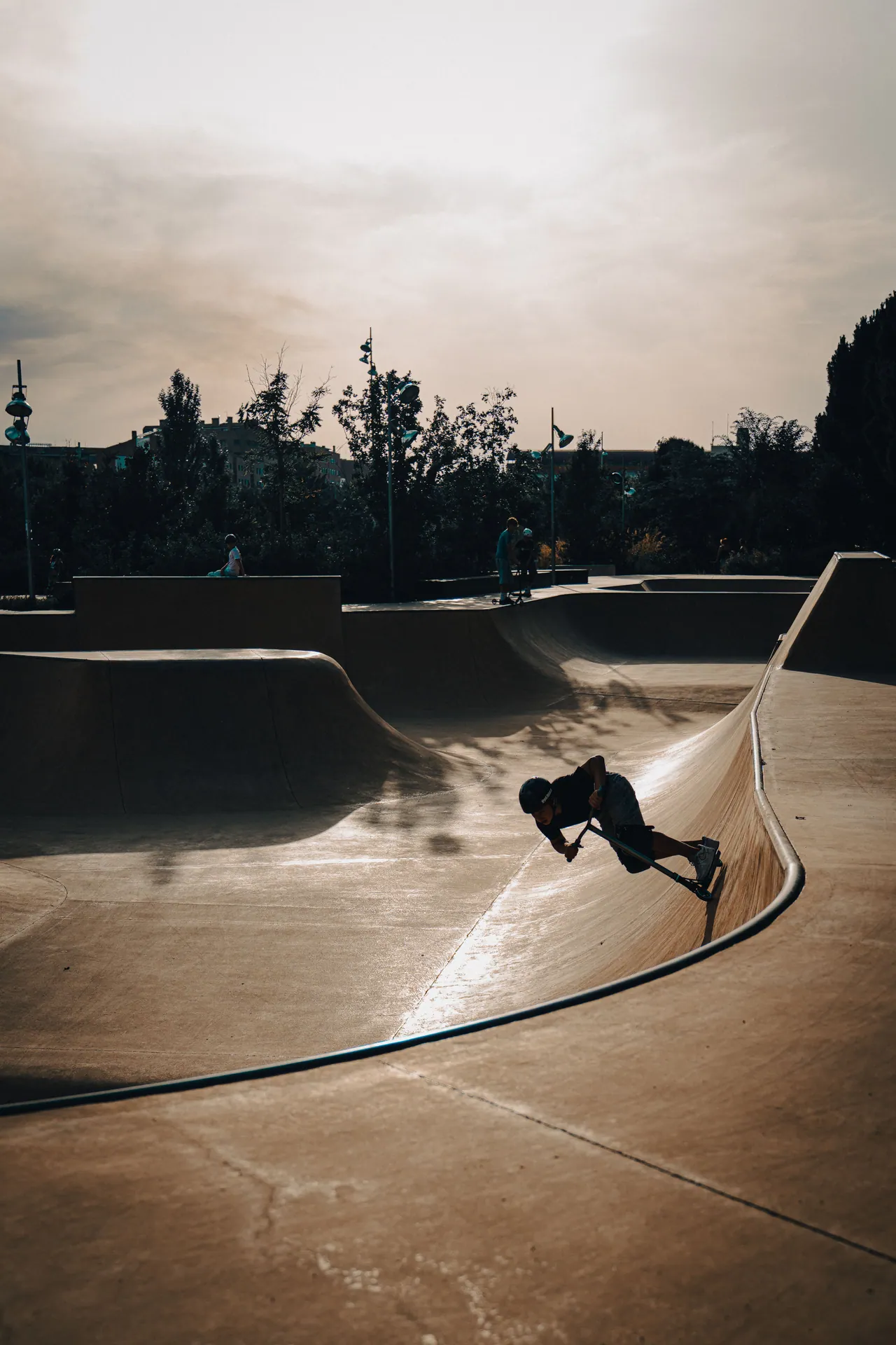 A skateboarder performs a trick in an urban skatepark at sunset, capturing dynamic motion and moody lighting.