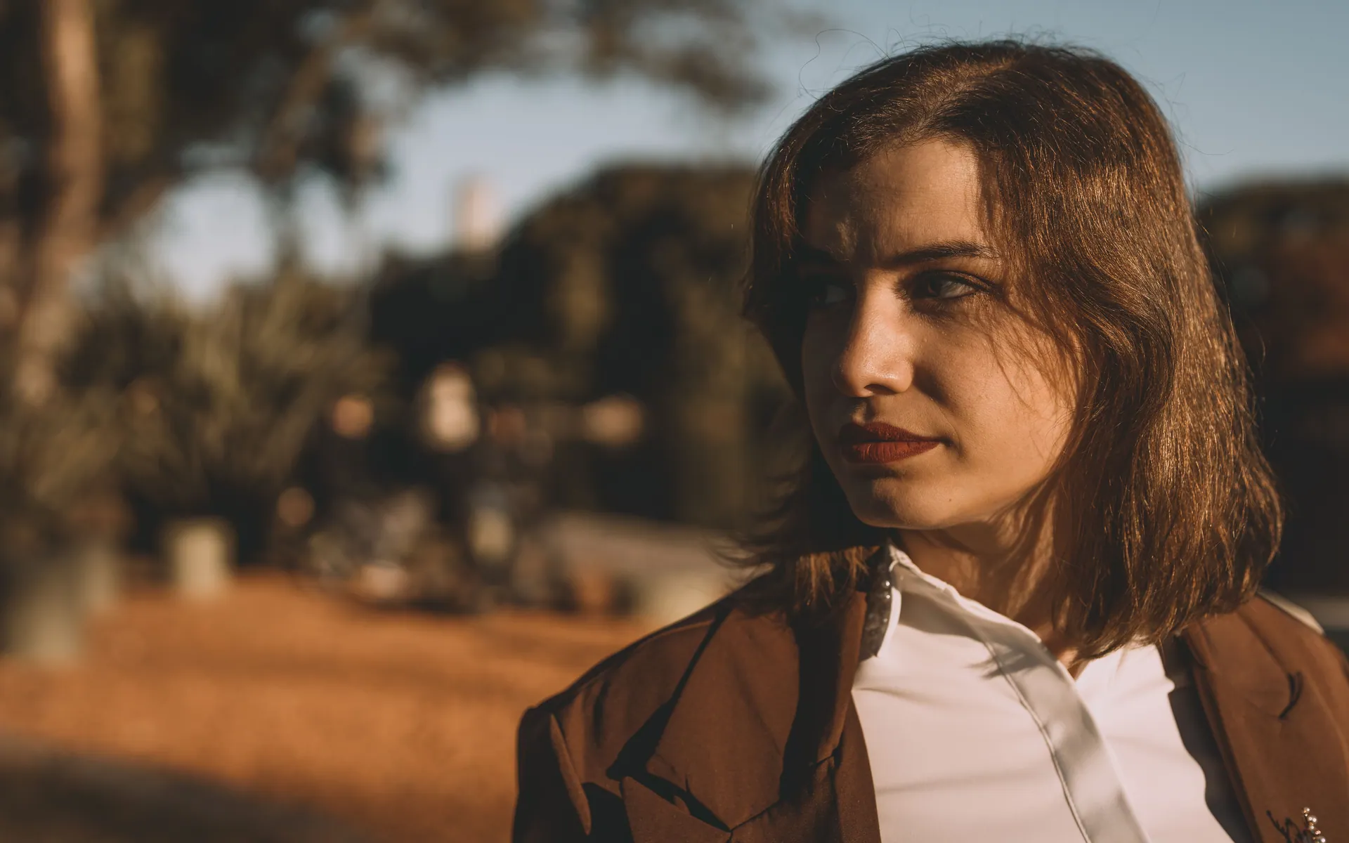 A young woman gazing thoughtfully outdoors in warm sunlight in Buenos Aires.