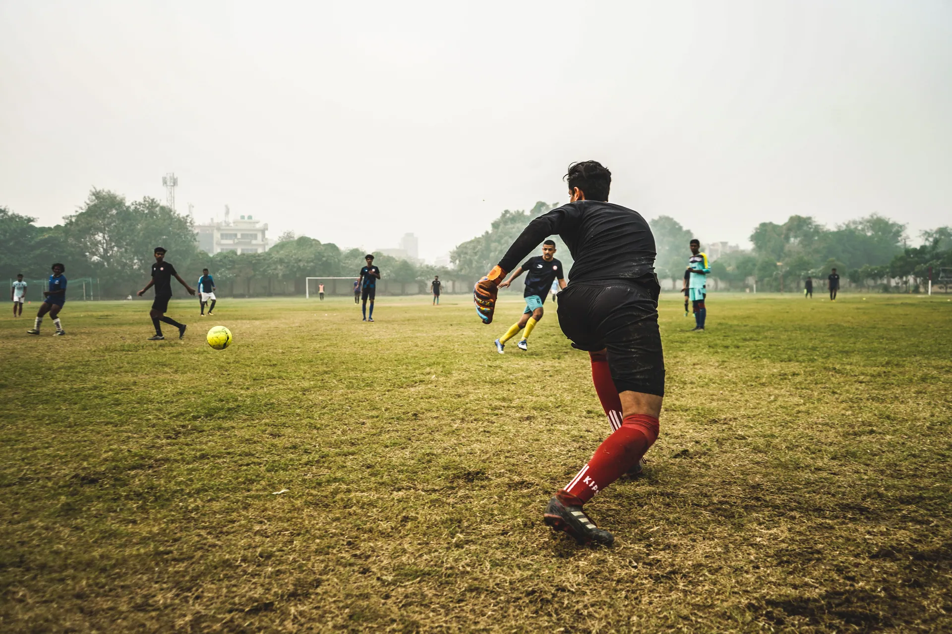 Energetic soccer game with players on a grassy field in India, showcasing teamwork and sportsmanship.