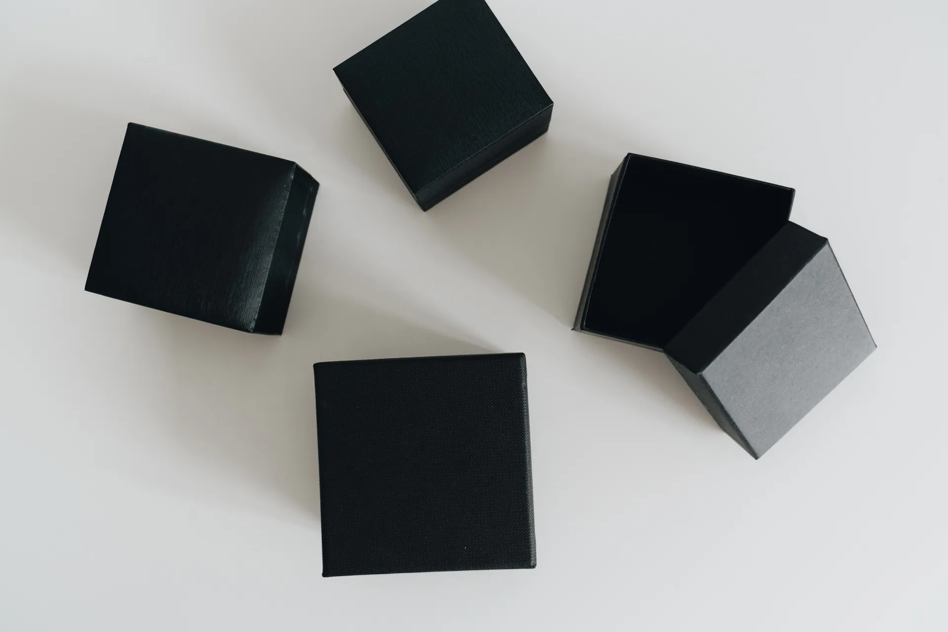 Aesthetic flat lay of black boxes open on a clean white surface.