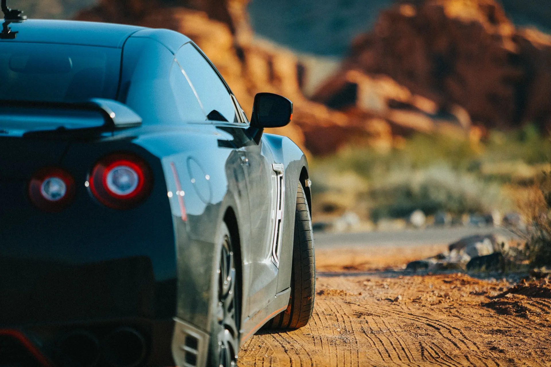 A black car parked in the scenic Nevada desert, showcasing its sleek back view.