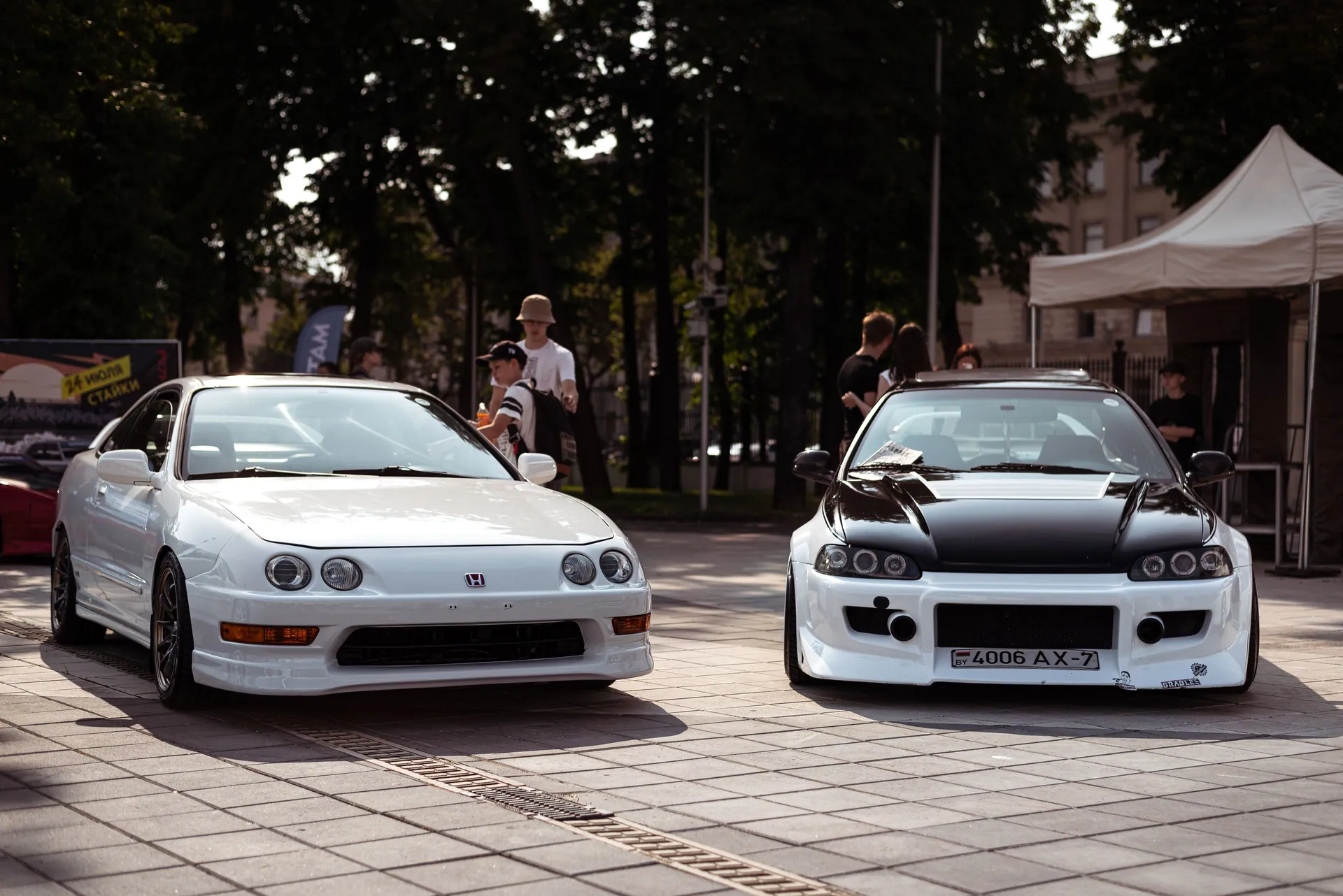 Showcase of modified Honda cars at an urban auto event with people in view.