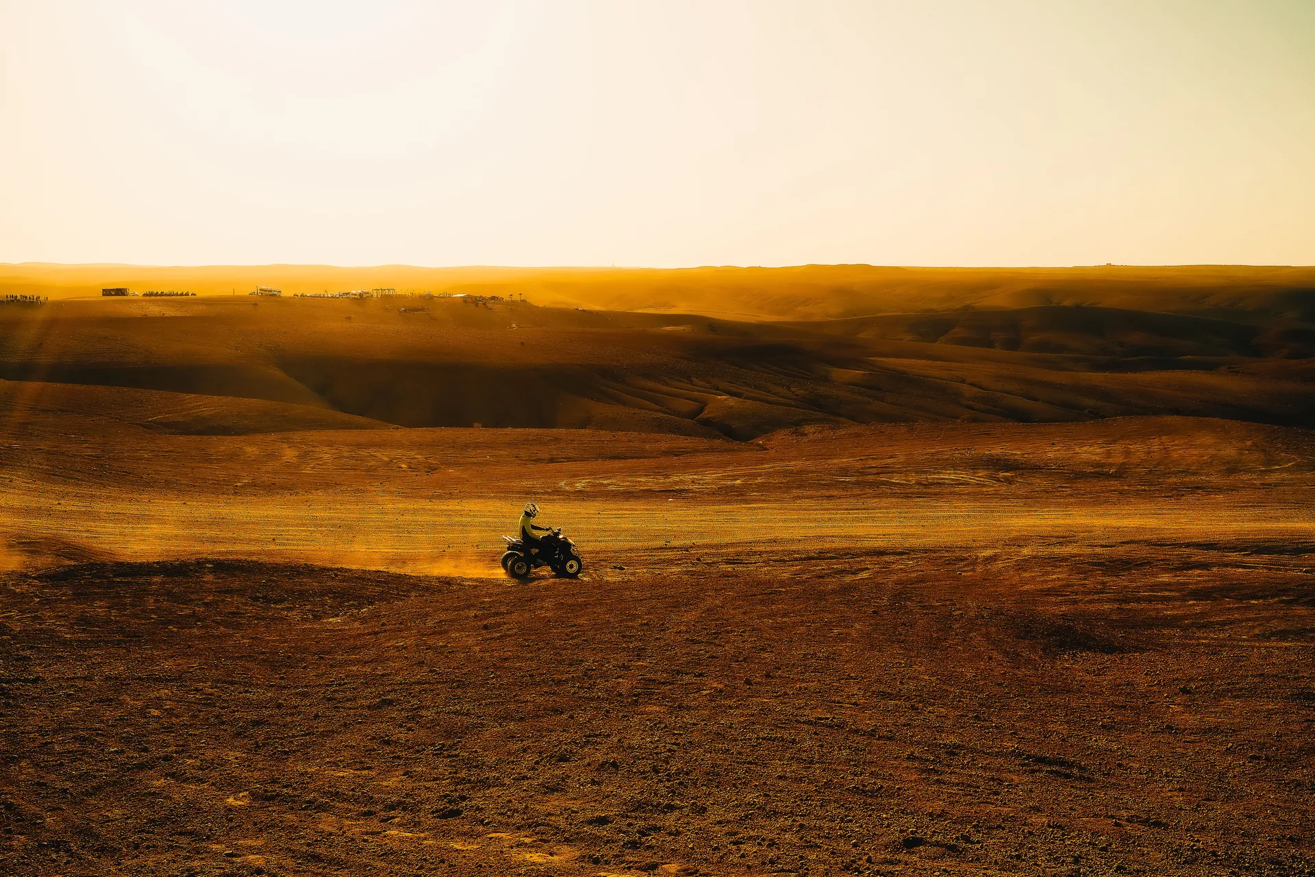 An ATV rider explores a wide open desert under a golden sunset, showcasing adventure and thrill.