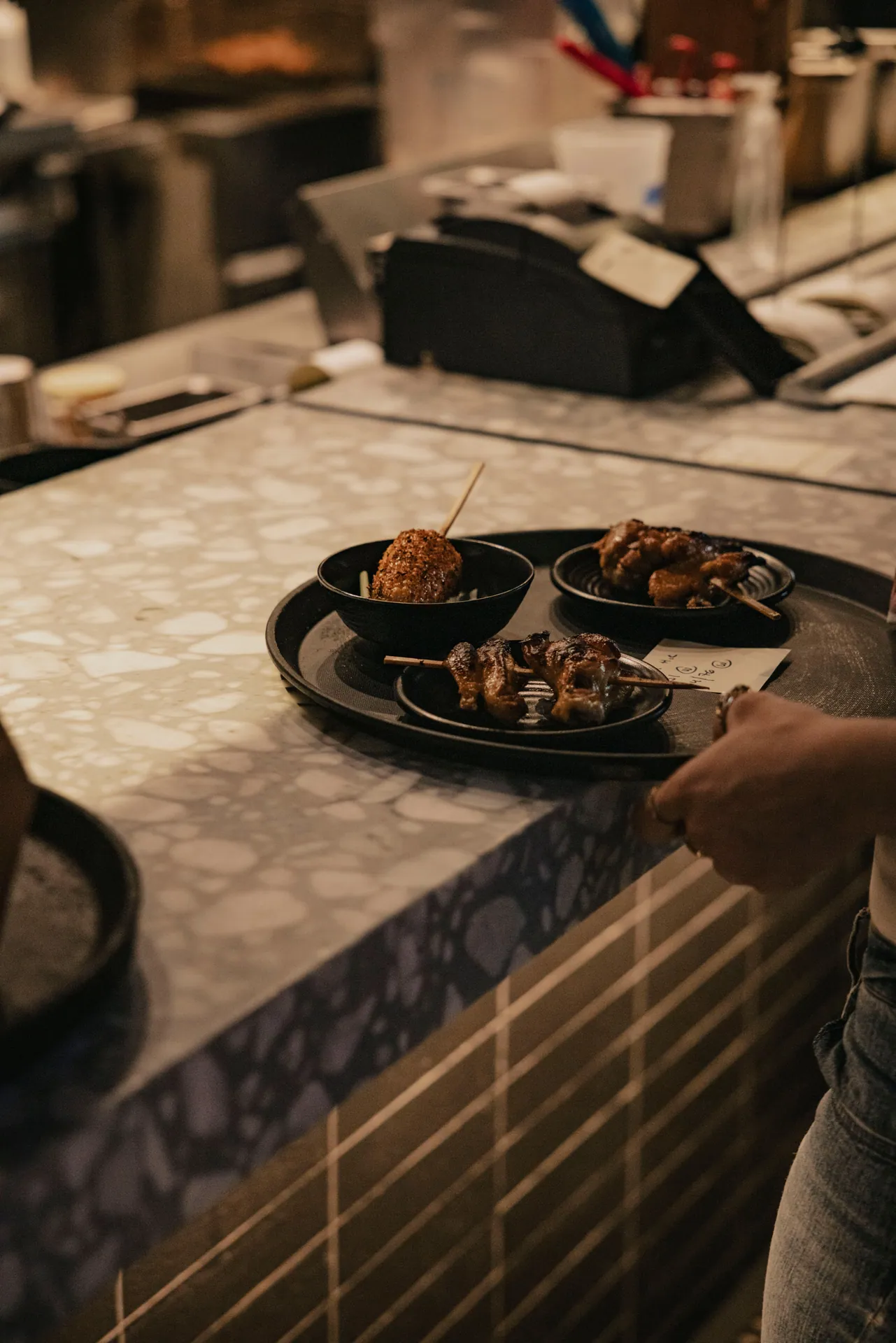 Cozy restaurant scene featuring skewers and dishes served on a tray, showcasing rustic dining vibes.