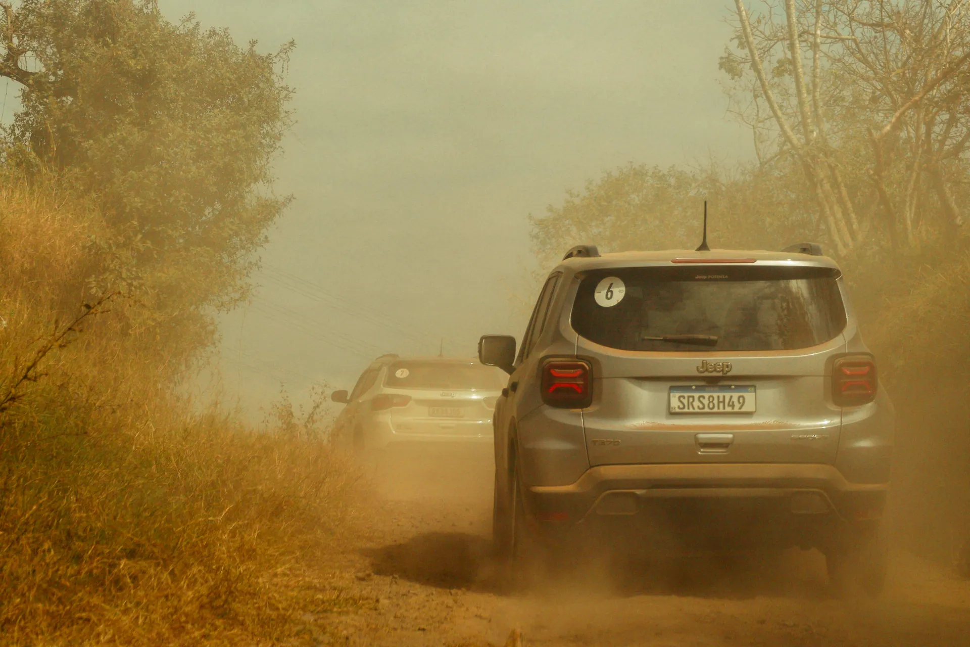 Two SUVs navigate a dusty off-road trail, creating a thrilling adventure scene.