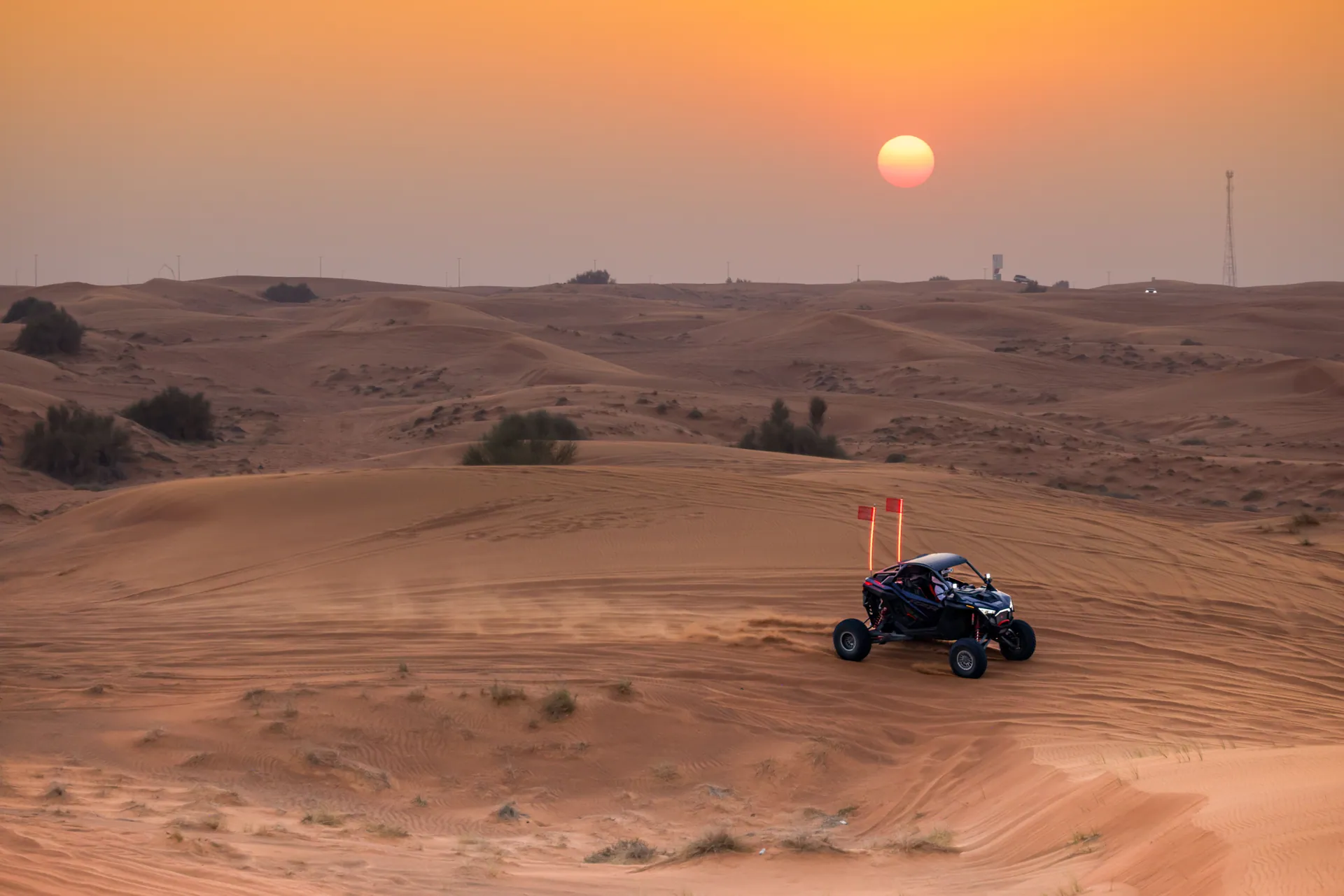 Dune buggy ride across desert dunes at sunset, highlighting adventure and nature.