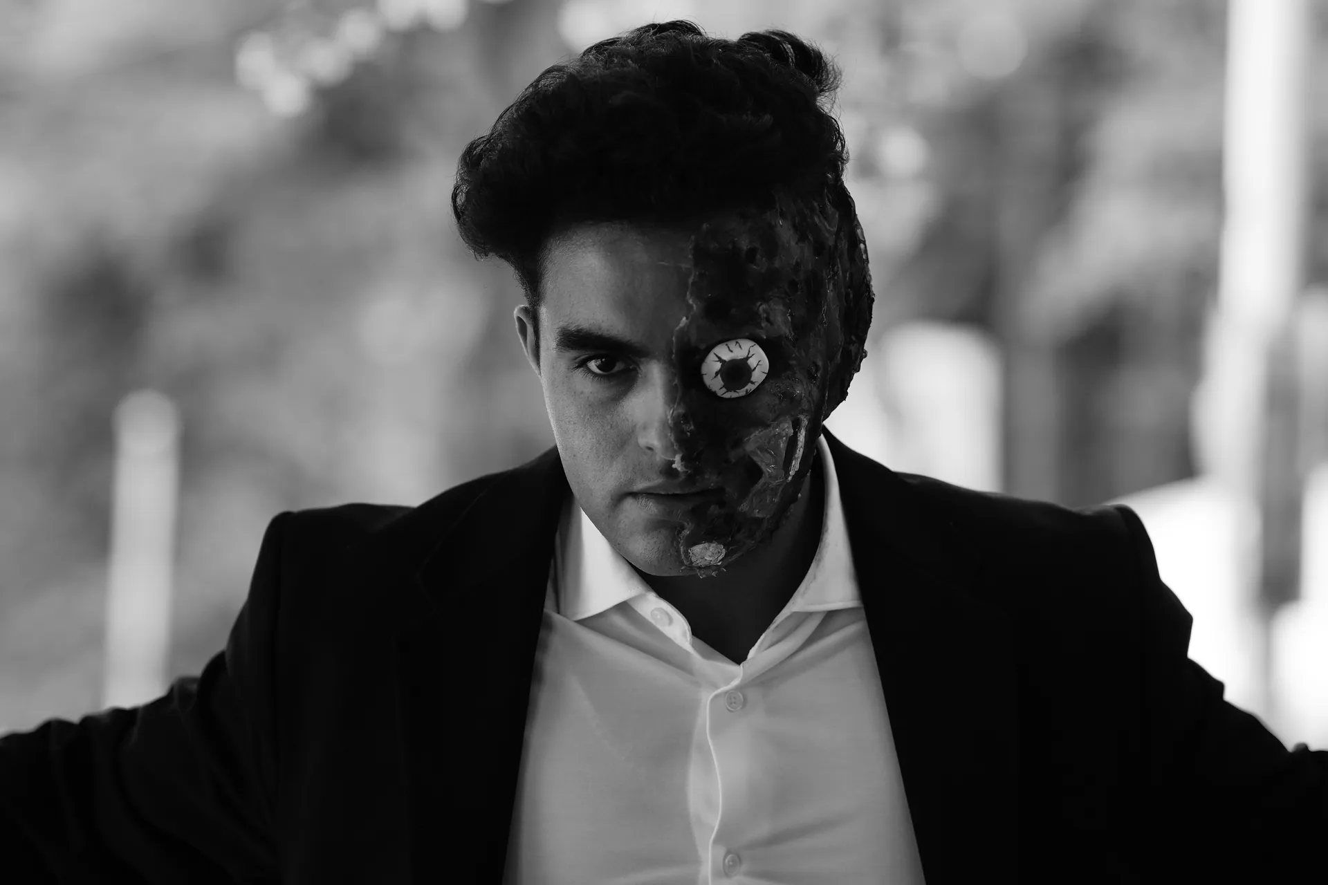Black and white portrait of a man with an artistic face mask, evoking mystery and drama.