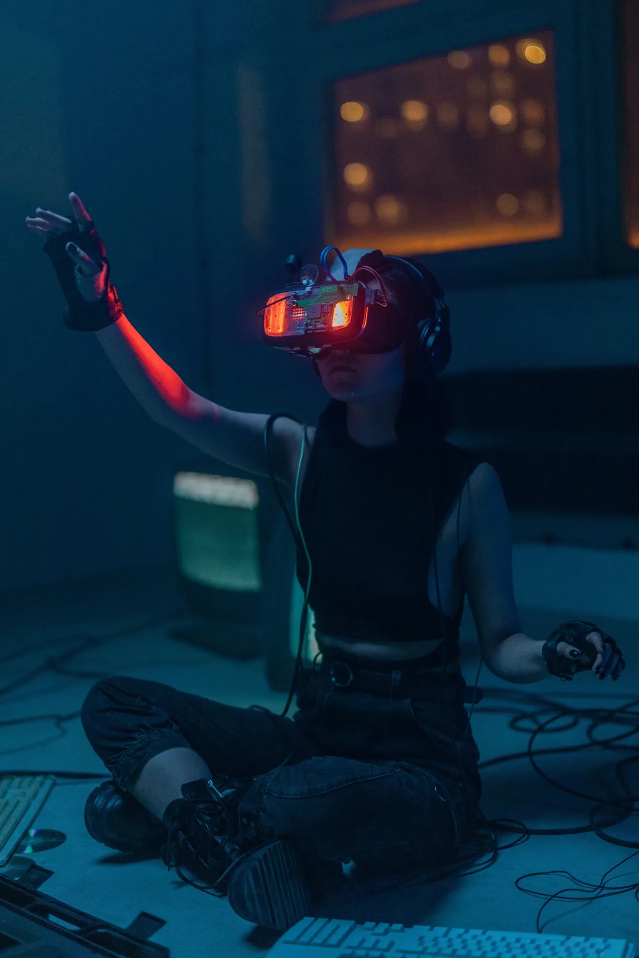 A woman wearing VR headset and gloves explores a virtual environment at night indoors.