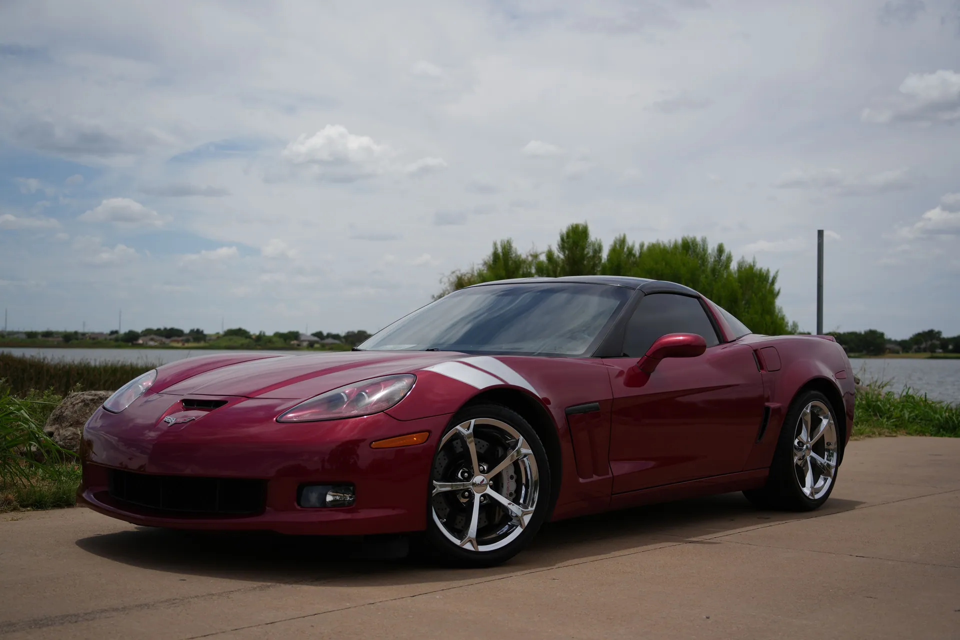 Red Corvette sports car parked on a scenic road in Wichita Falls, Texas, under a cloudy sky.