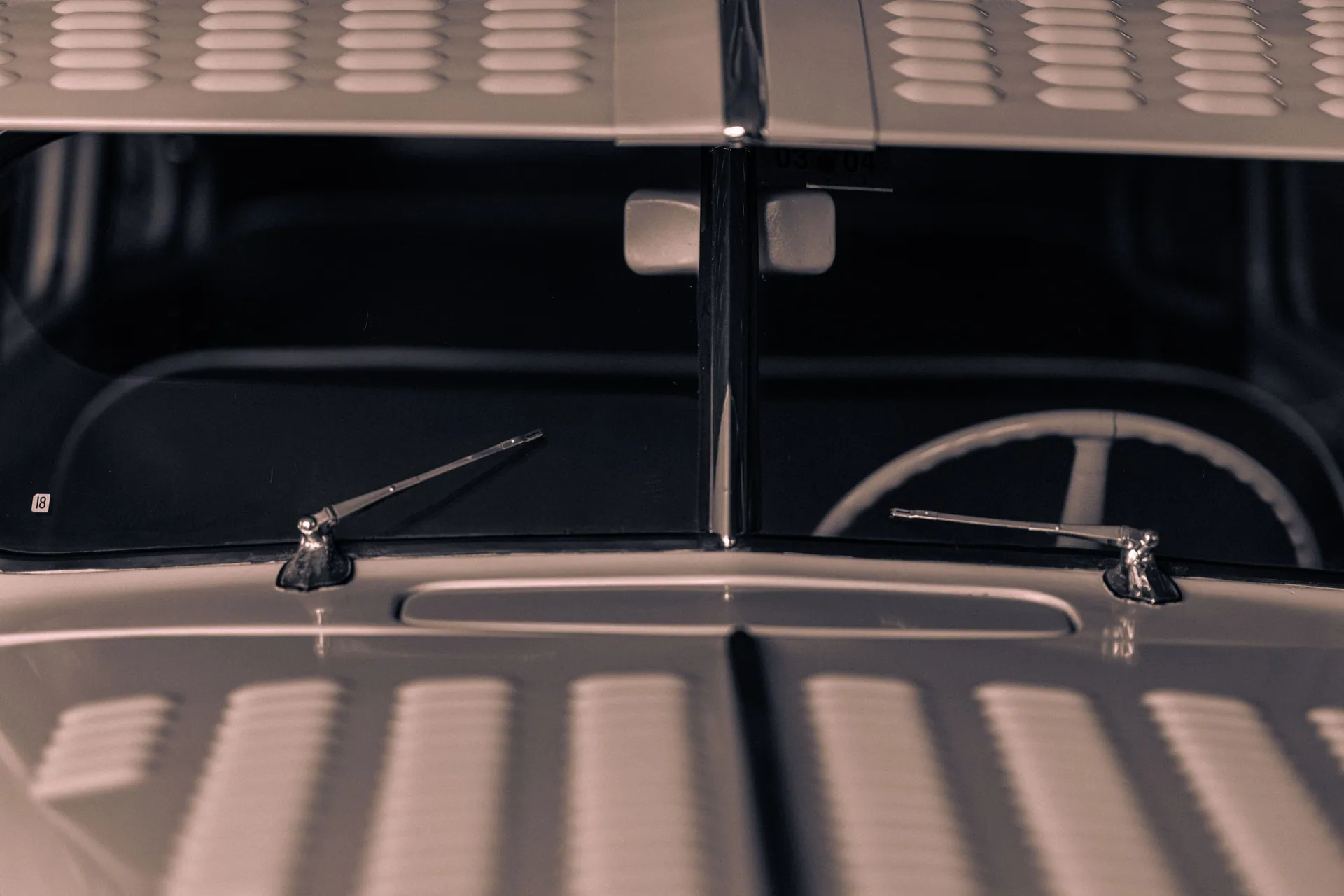Detailed view of a classic car's windshield and chrome wipers, showcasing automotive design.