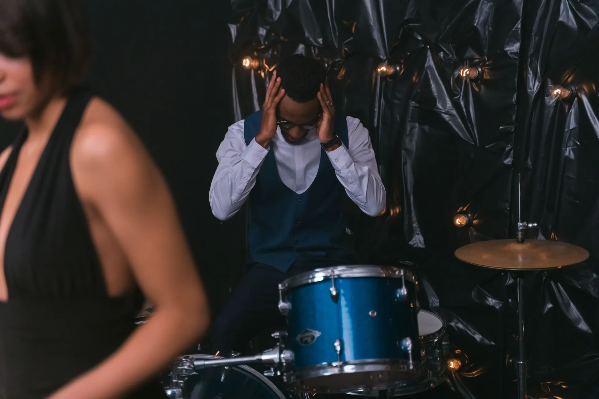 Musician playing drums in a dimly lit studio setting with a focus on expression and emotion.