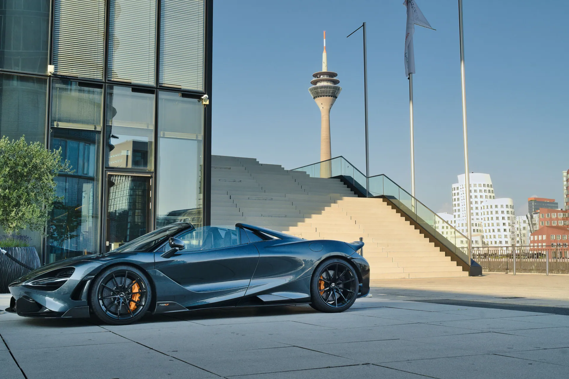 Stunning luxury sports car parked outdoors with the iconic Rhine Tower in Düsseldorf, Germany.