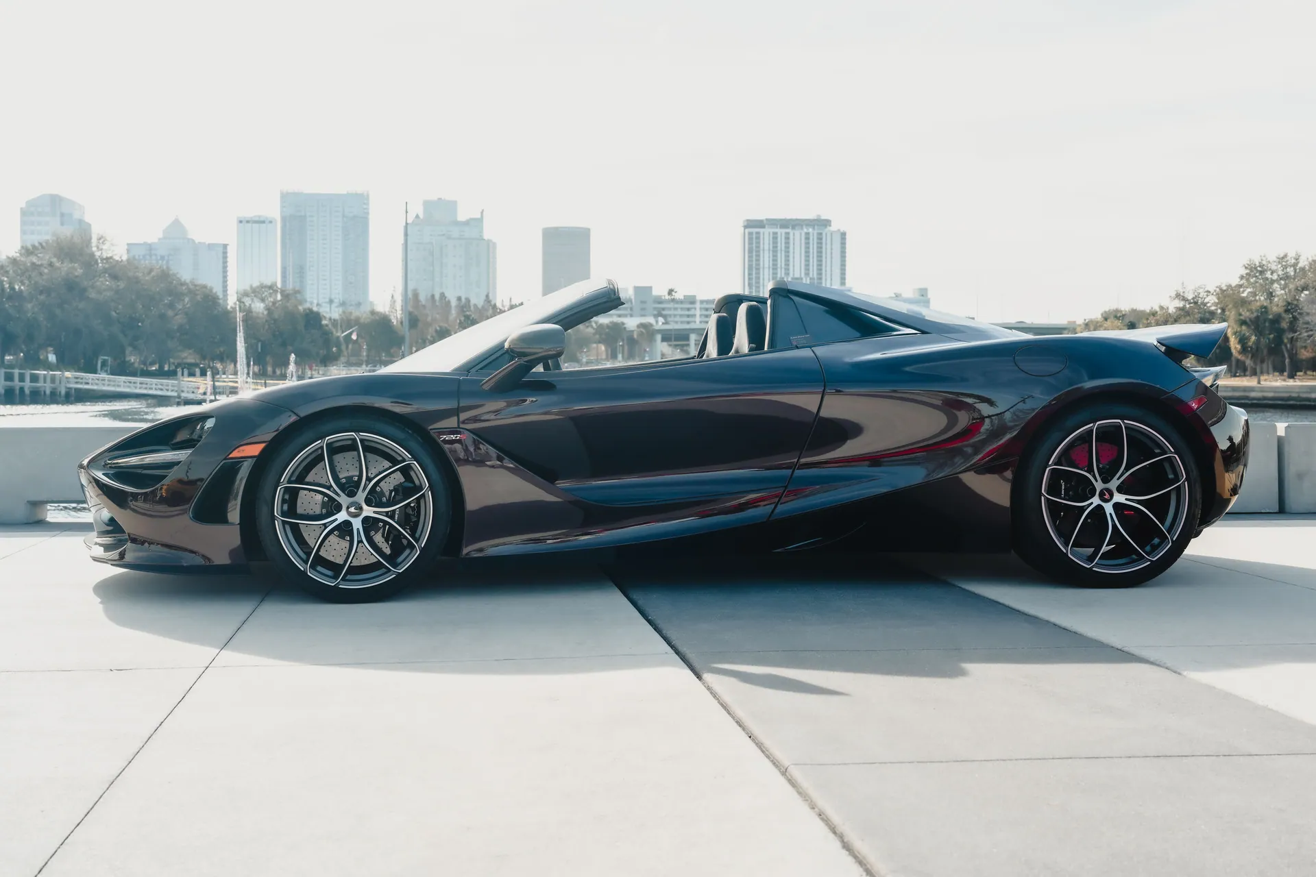 Sleek sports car parked near waterfront with city skyline in background