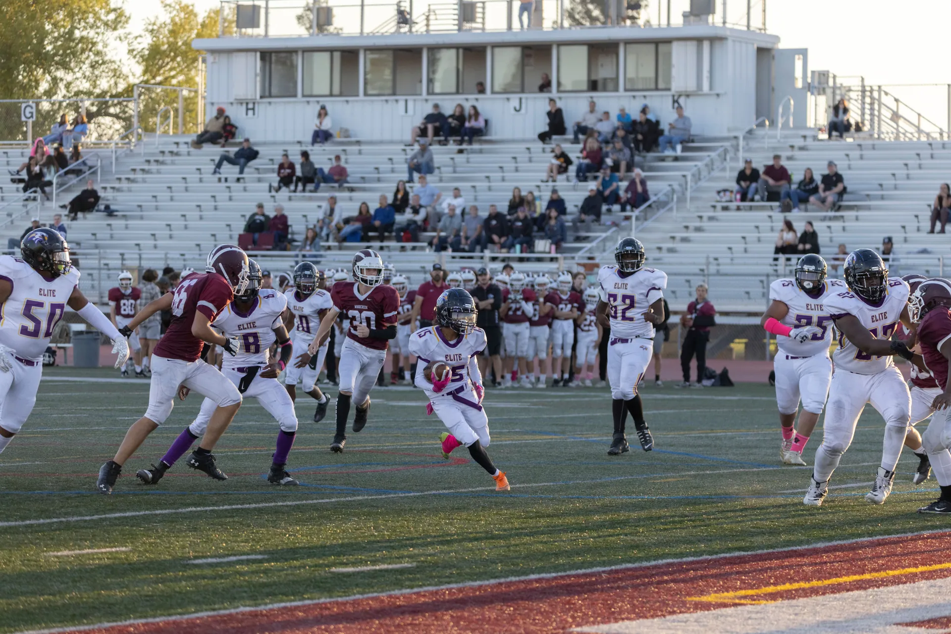 Exciting football match with young athletes in action on the field at an outdoor stadium.