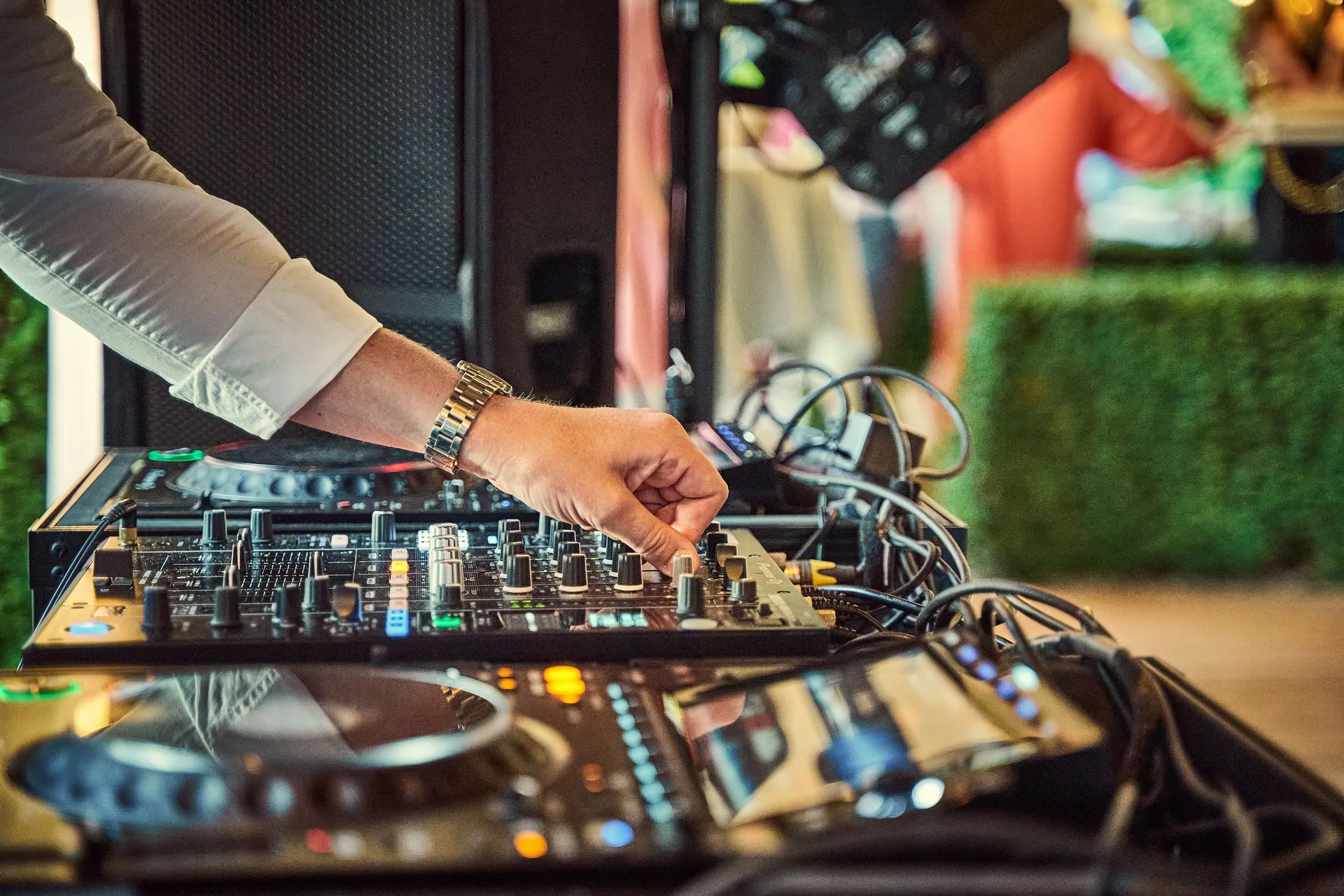 Close-up of DJ adjusting an audio mixer outdoors, showcasing modern music equipment.