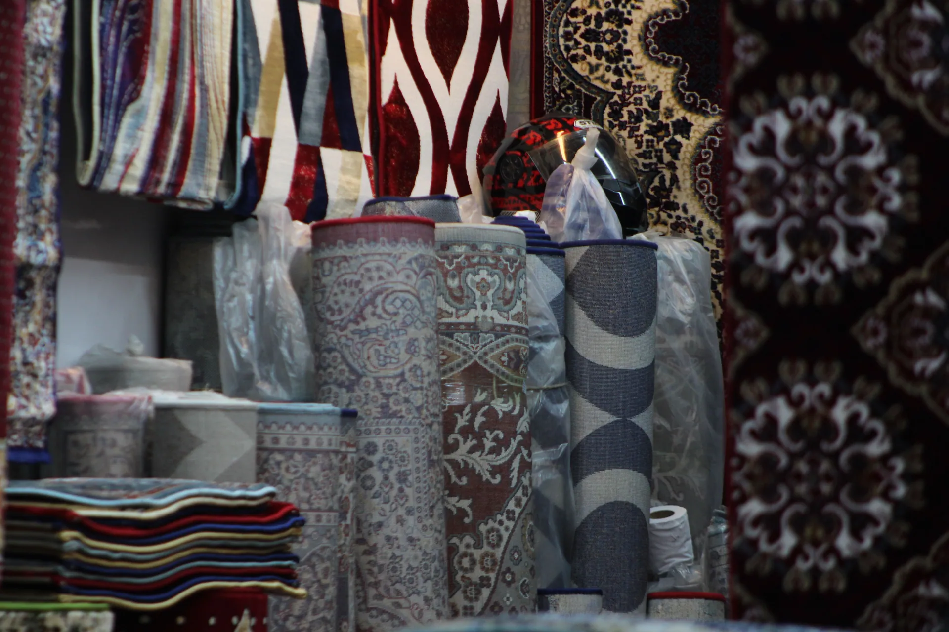 A vibrant collection of patterned and textured fabric rolls in a market setting.