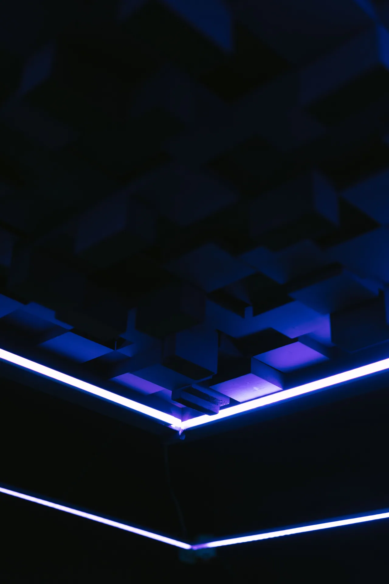 A dark geometric ceiling illuminated by vibrant blue LED strip lights, creating a modern ambiance.