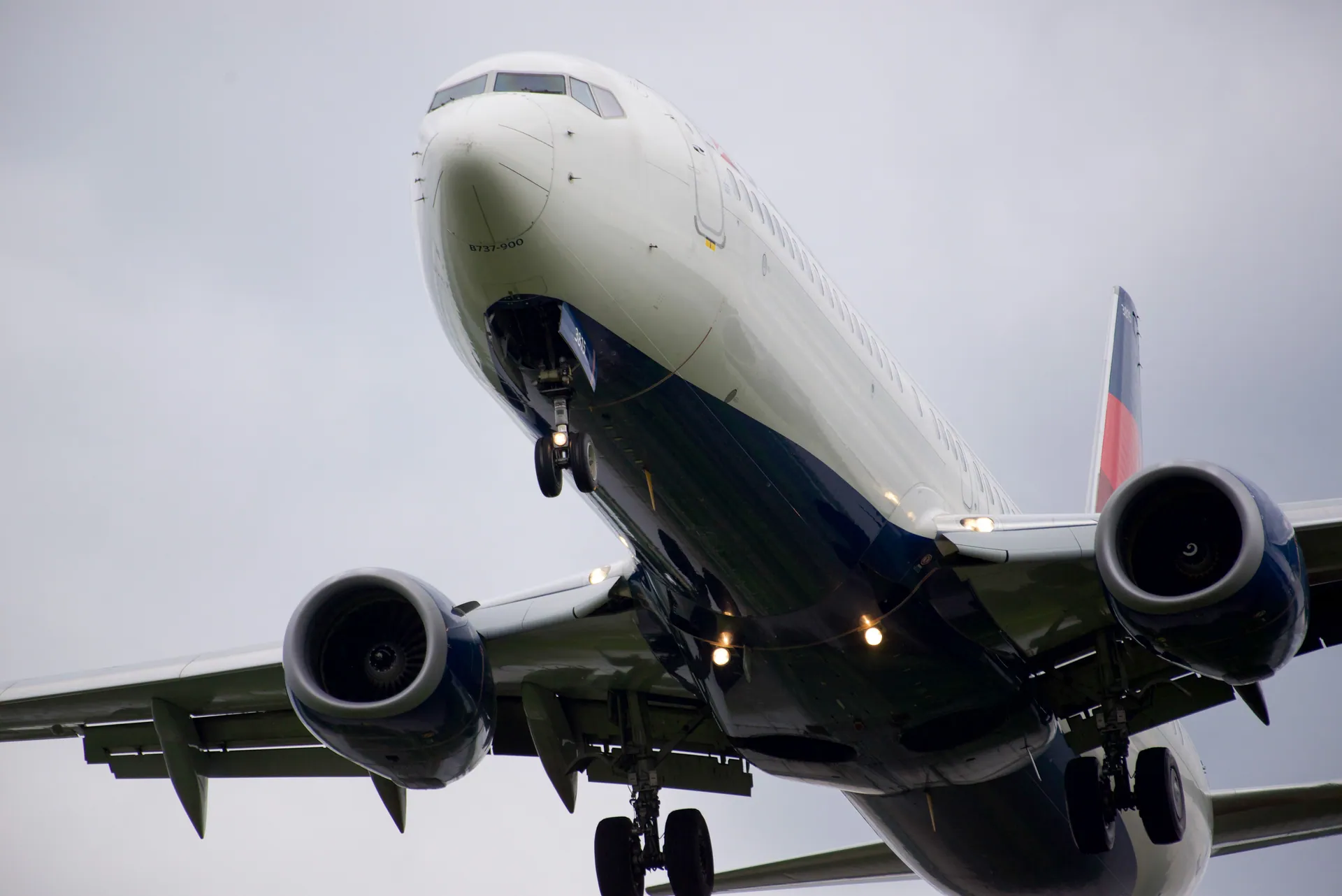 Close-up, low-angle shot of an airplane in flight against a cloudy sky.