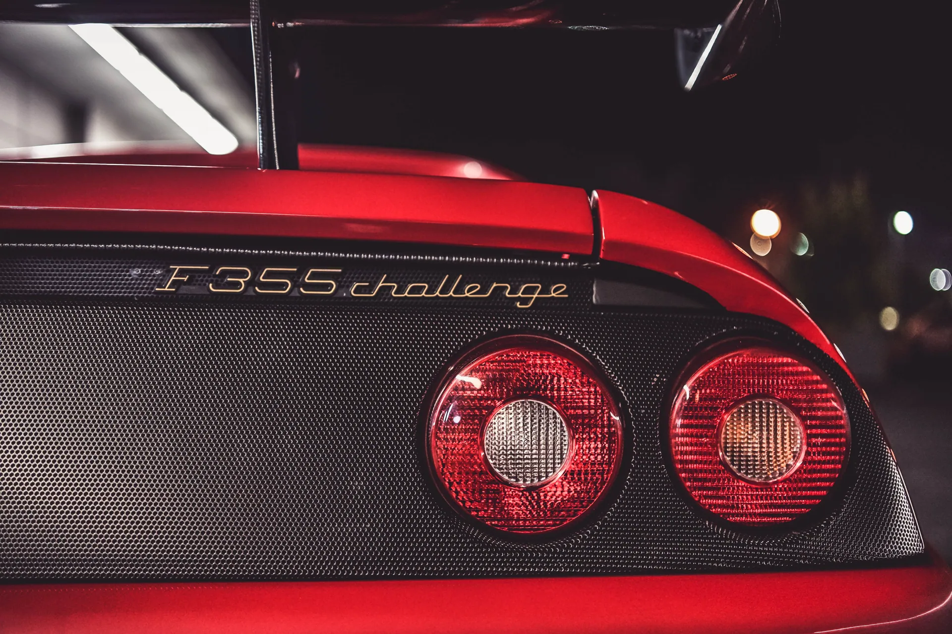 Detailed view of a Ferrari F355 Challenge taillight showcasing luxury design at night.
