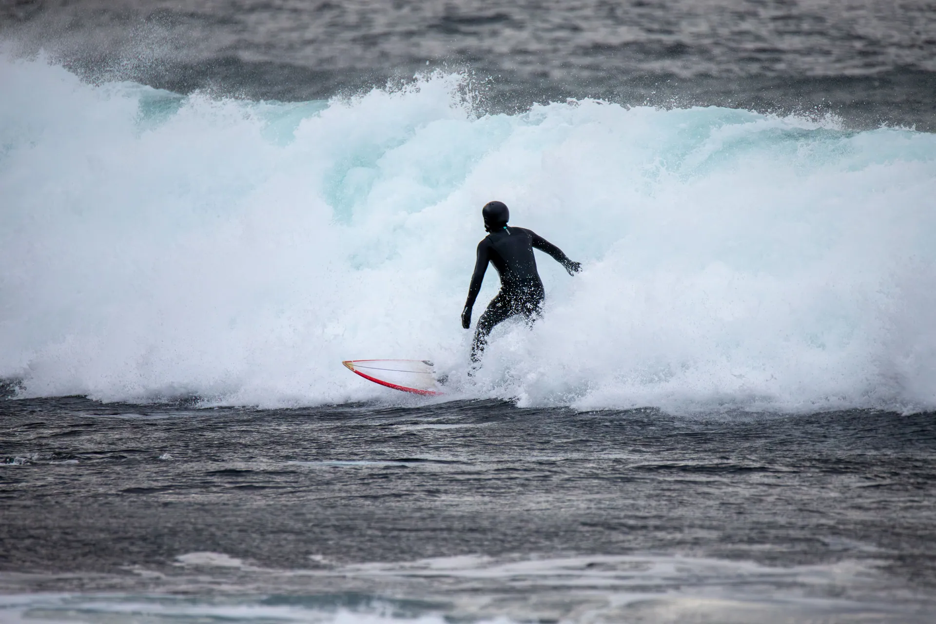Surfer in wetsuit tackling Norway's icy waves in winter.