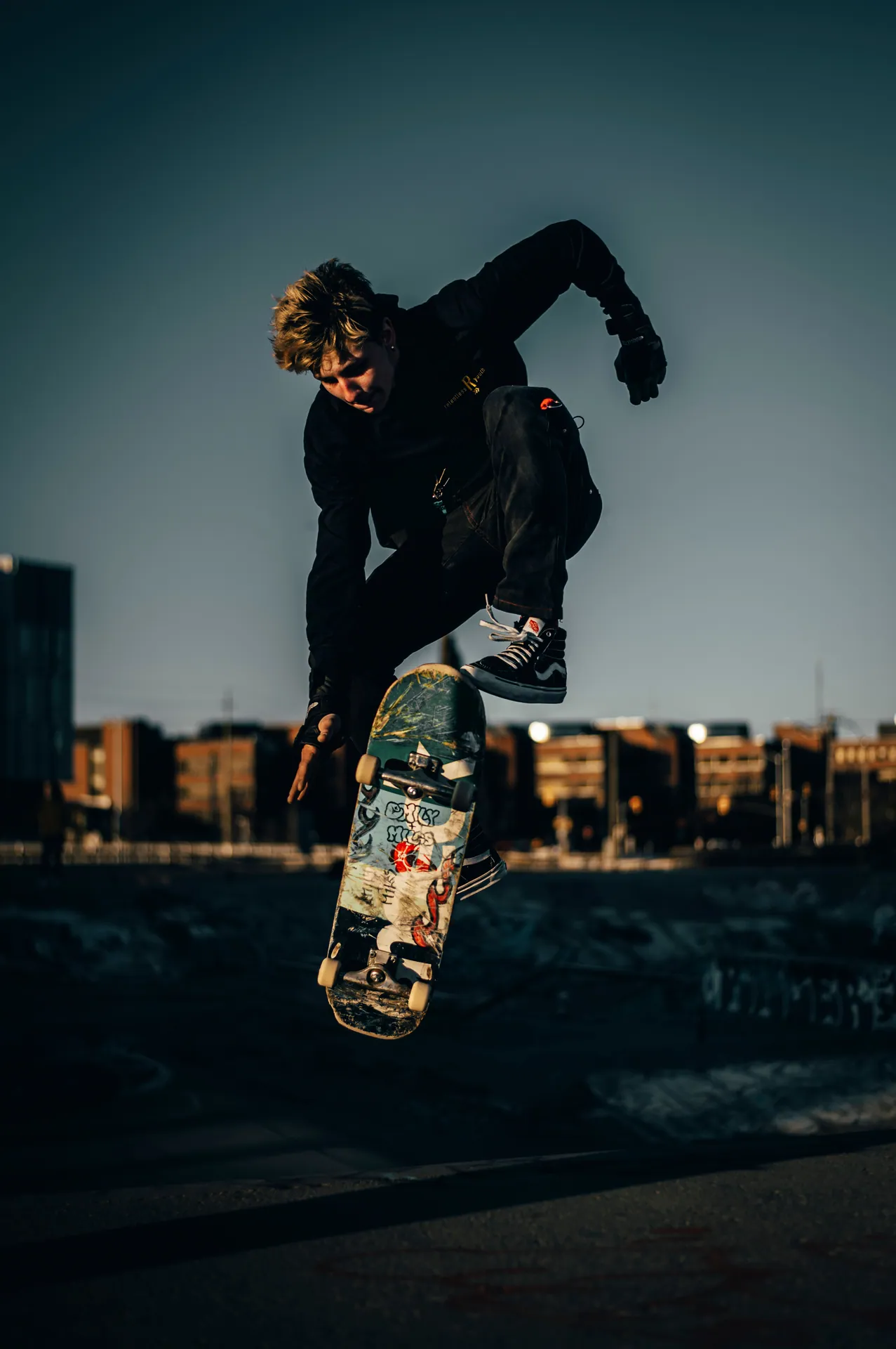 A skateboarder performs a trick mid-air against a city backdrop.