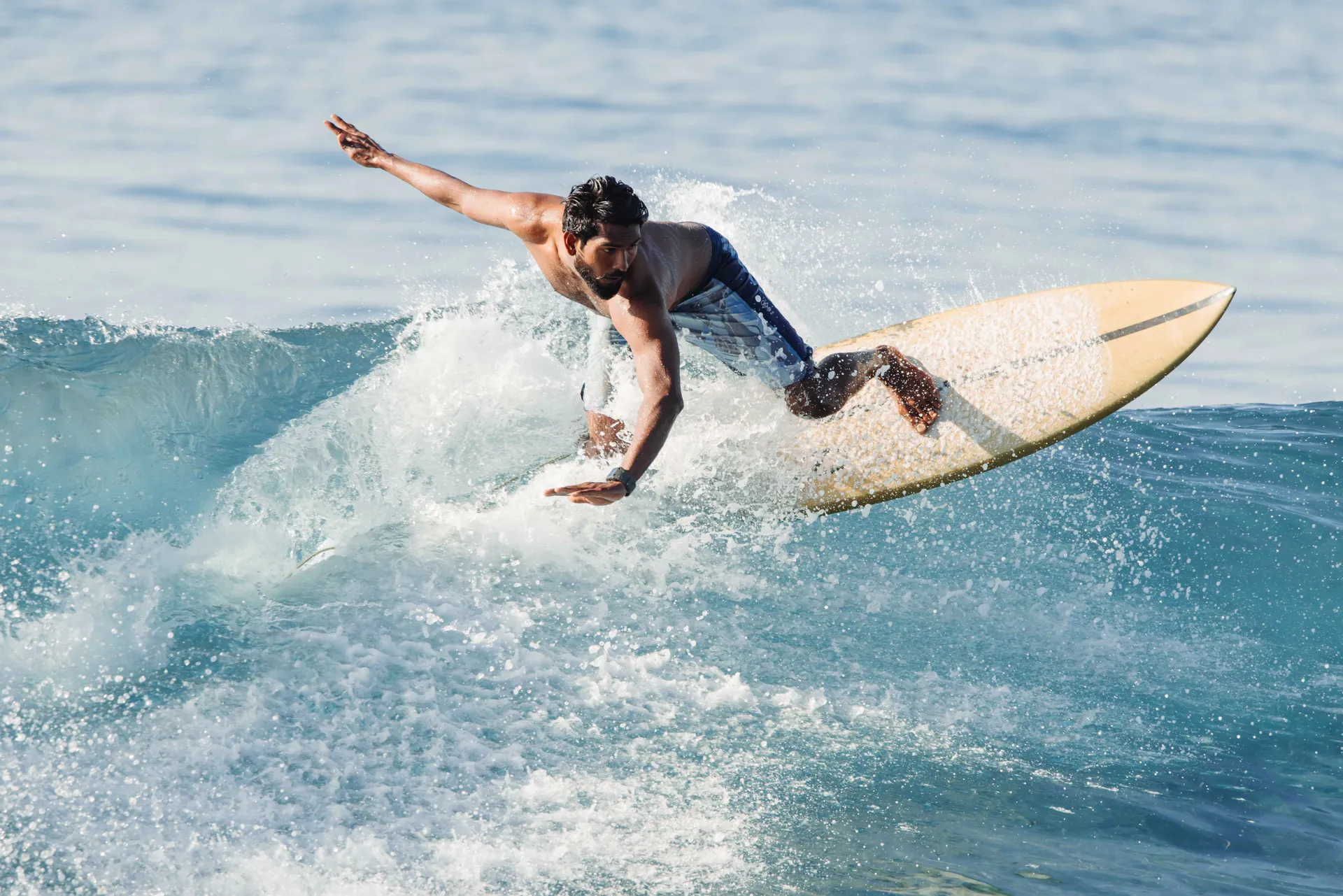 A surfer rides a powerful wave in the tropical waters of the Maldives.