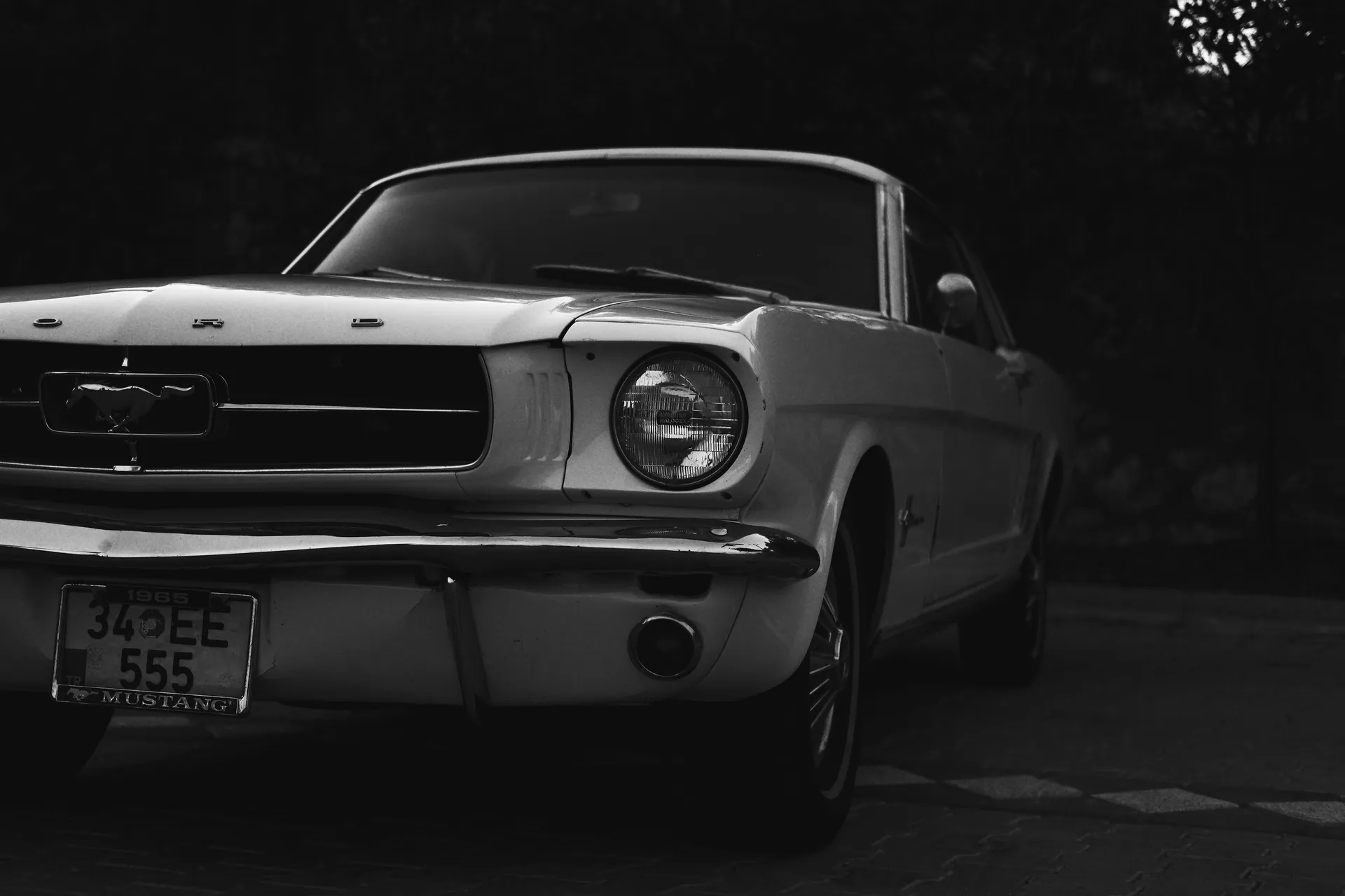 Close-up of a vintage Ford Mustang in grayscale, showcasing classic automotive design.
