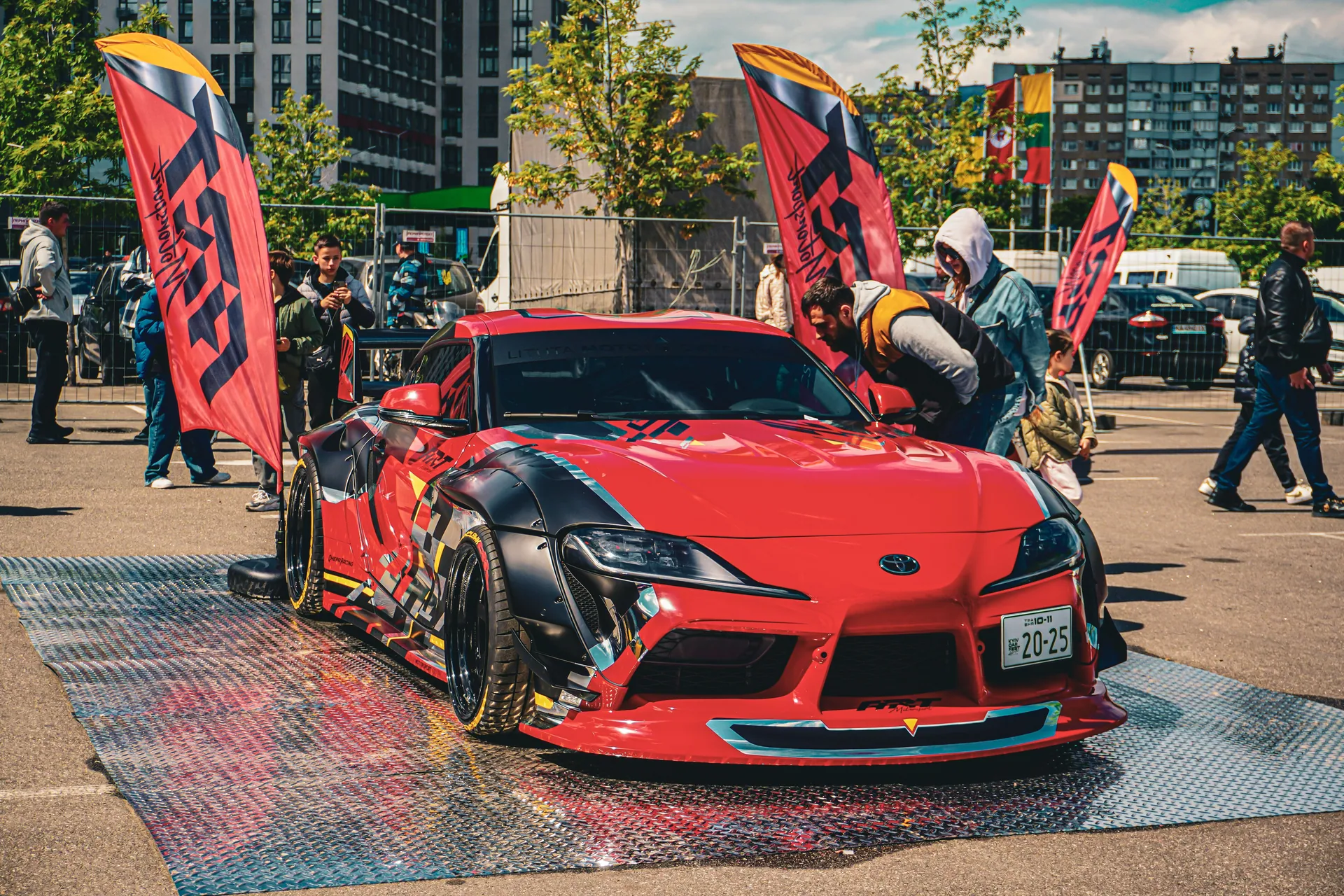 Vibrant red sports car showcased outdoors among enthusiasts at a car exhibition in Kyiv, Ukraine.