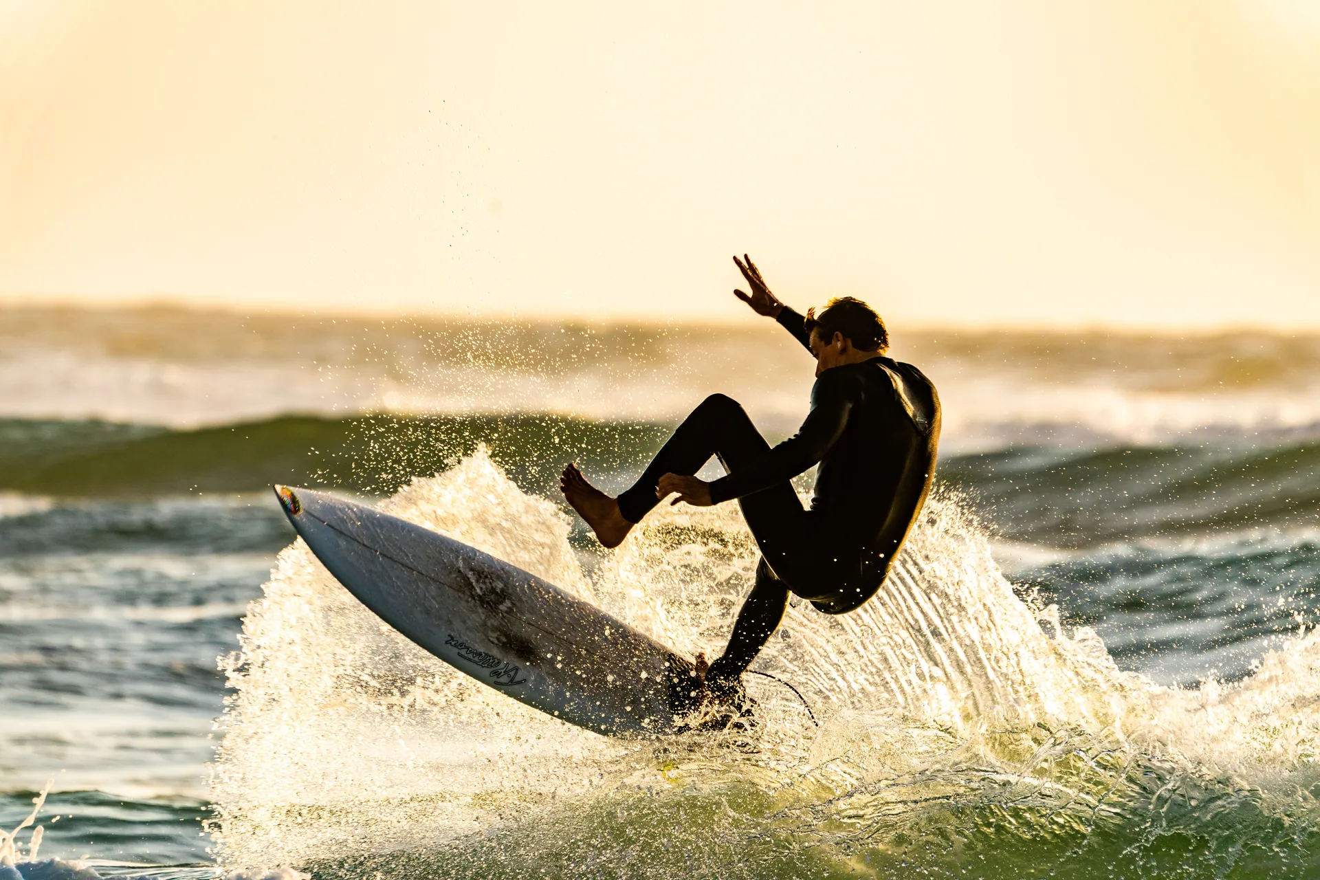 Experience the thrill of a surfer catching waves during a vibrant sunrise session.