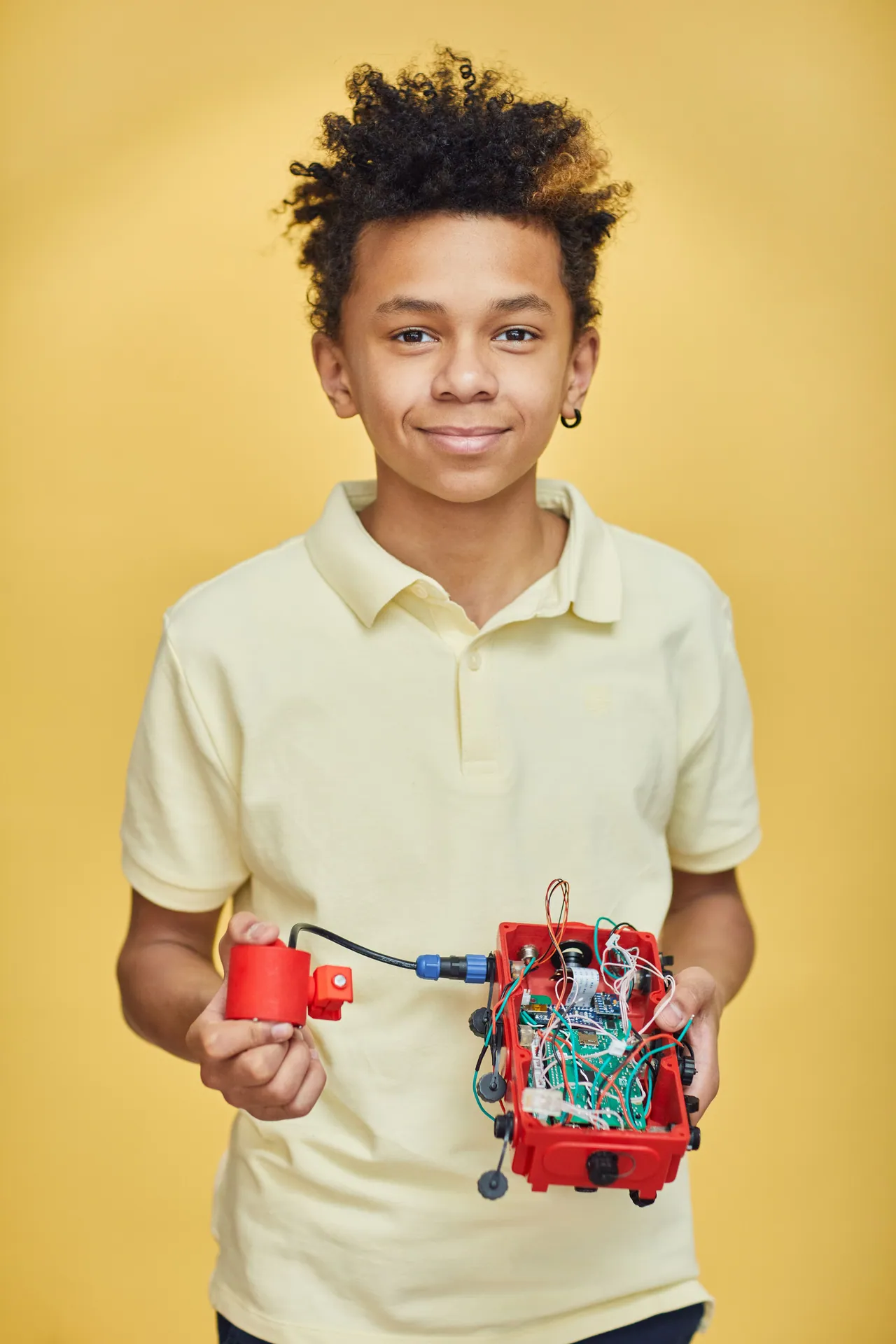 Teenage boy proudly displays his homemade robotics project, showcasing creativity and STEM skills.