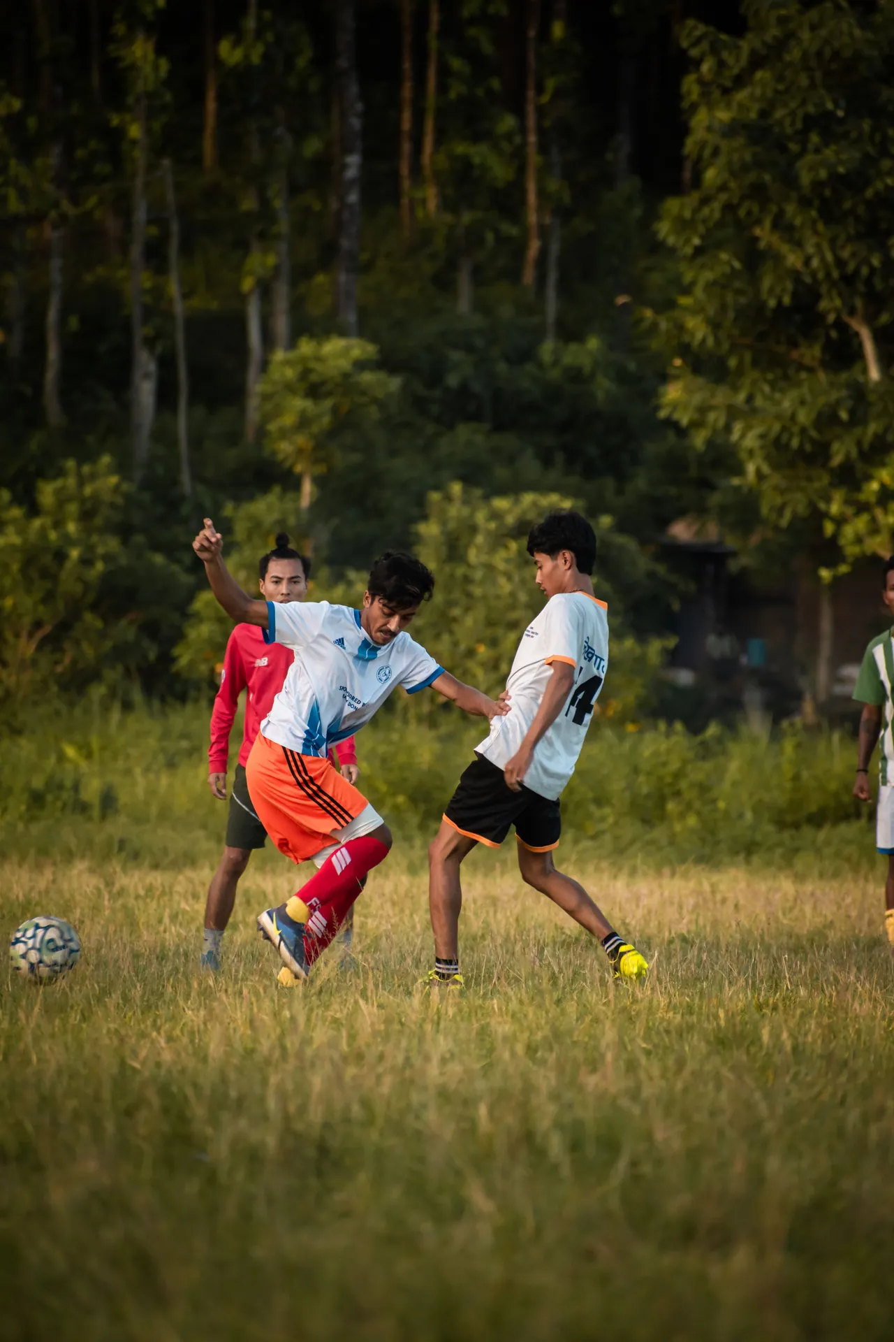 Young men enjoy a soccer match outdoors in casual sports attire on a grassy field.