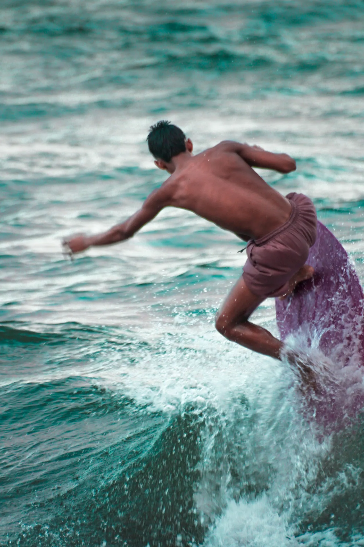 Dynamic image of a young man surfing vibrant waves in Bicol, Philippines.