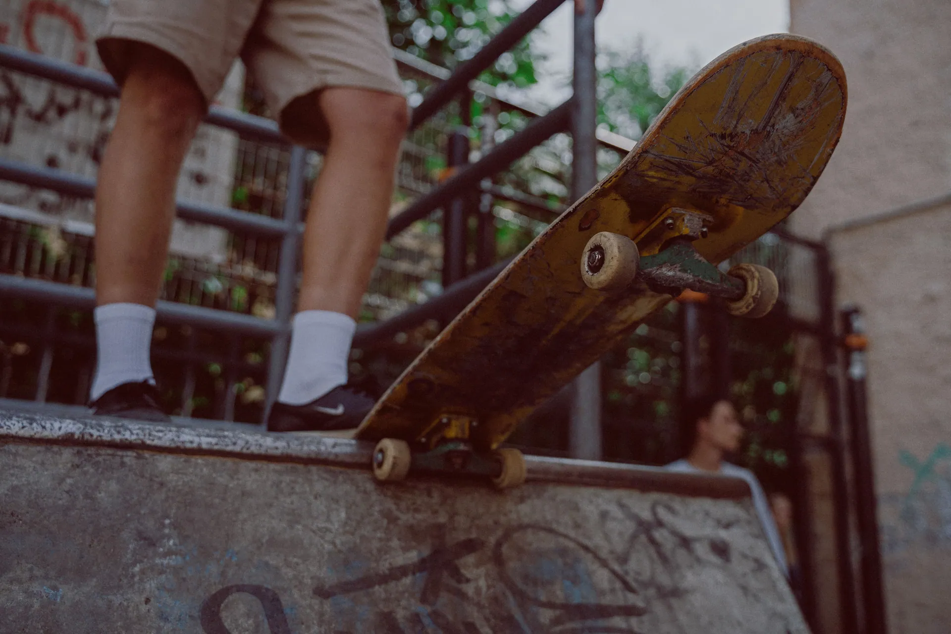 A skateboarder standing on a ramp with graffiti, ready to skate.