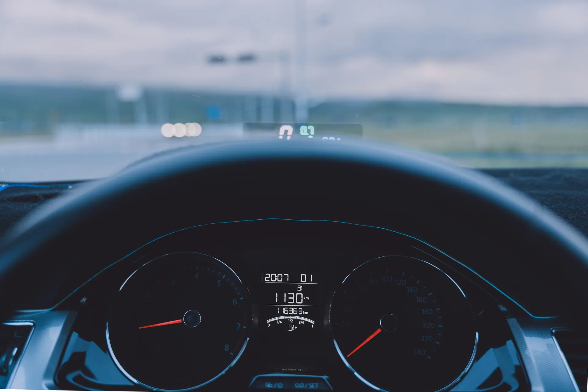 View from inside a car showing dashboard and steering wheel on an open road.