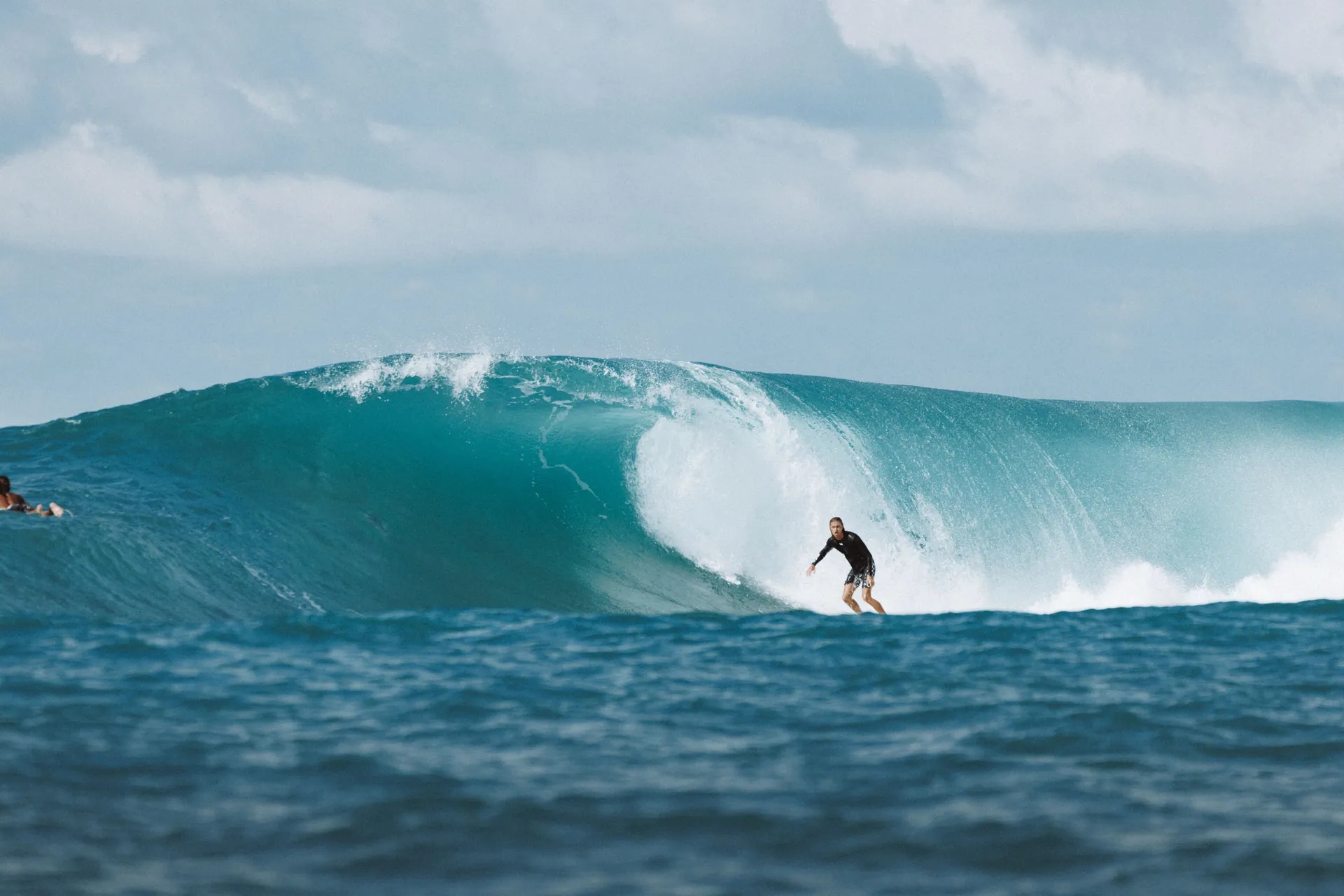 Surfer riding a massive ocean wave in Bali, capturing the thrill and beauty of water sports.